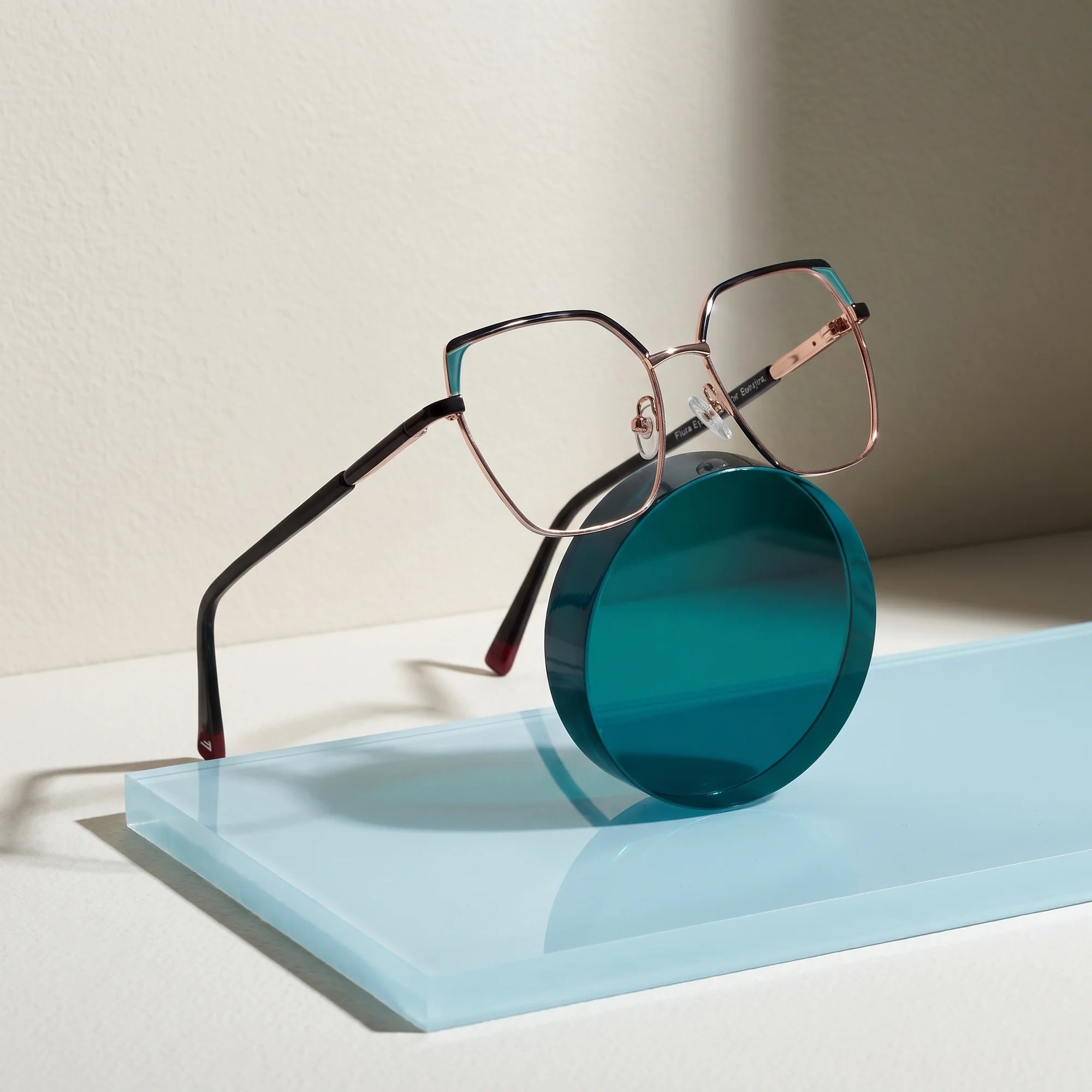 Fiore 3971 eyeglasses in black gold – on a cobalt acrylic disc in soft daylight