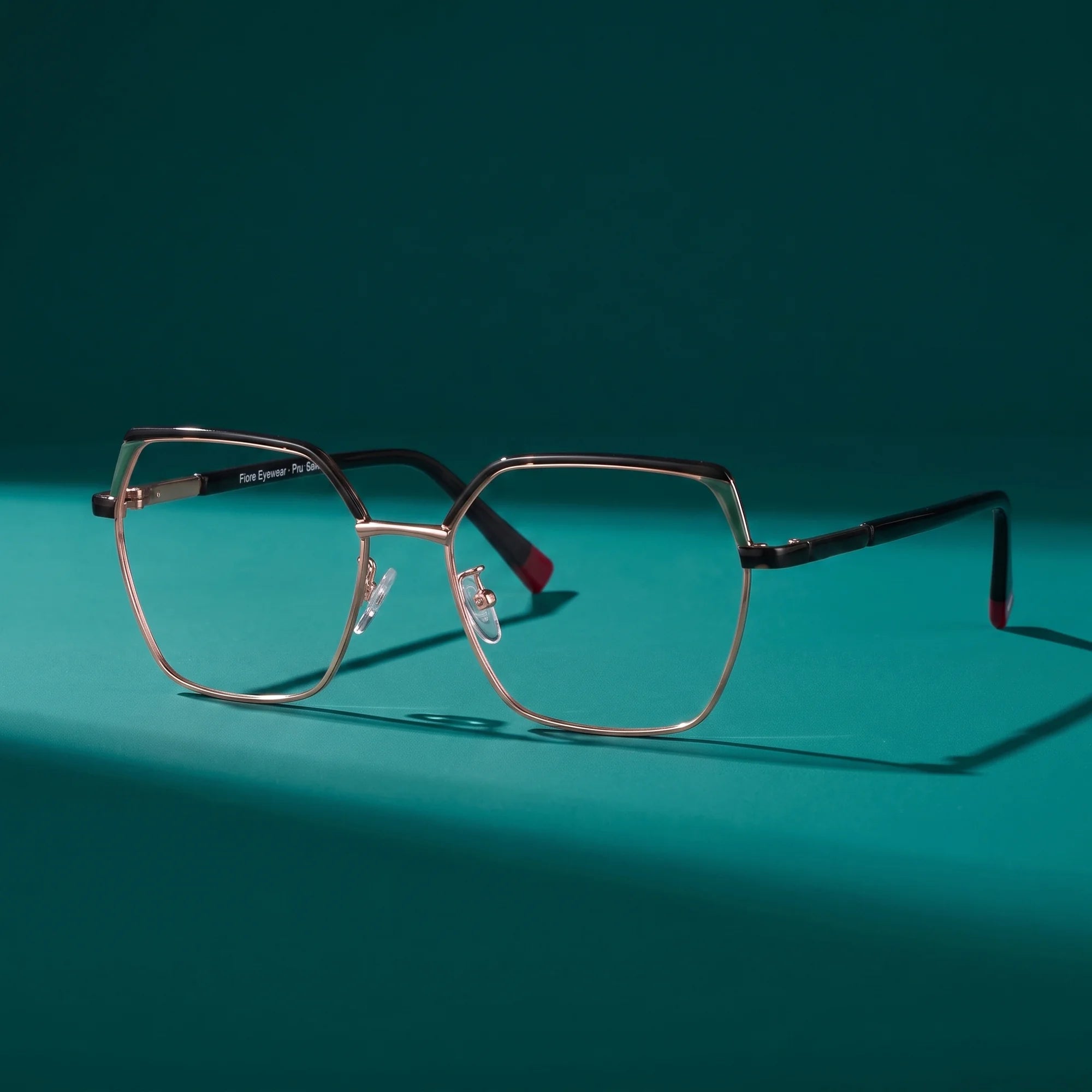 Fiore 3971 eyeglasses in black gold – still life on a seamless teal studio backdrop
