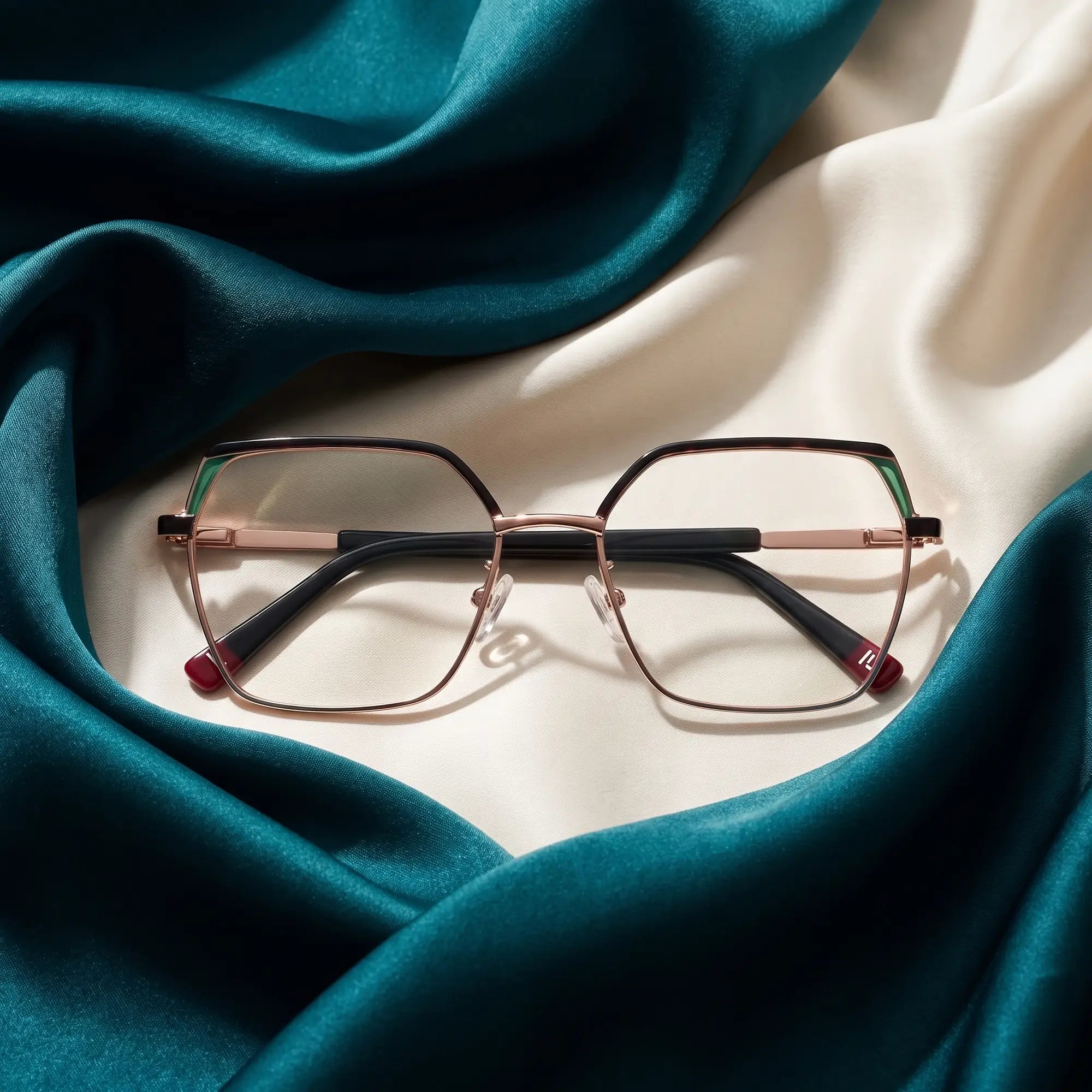 Fiore 3971 eyeglasses in black gold – resting on draped teal and ivory silk