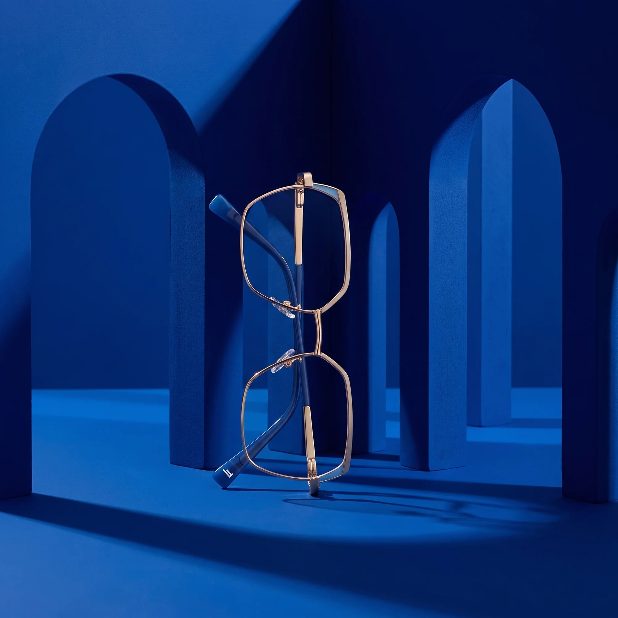 Fiore 3971 eyeglasses in grey gold – staged on a sculptural cobalt architecture set
