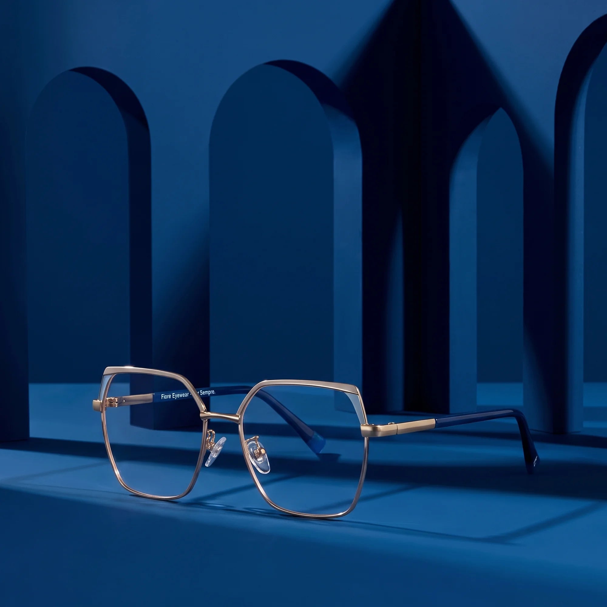 Fiore 3971 eyeglasses in grey gold – displayed on a midnight blue podium among arches