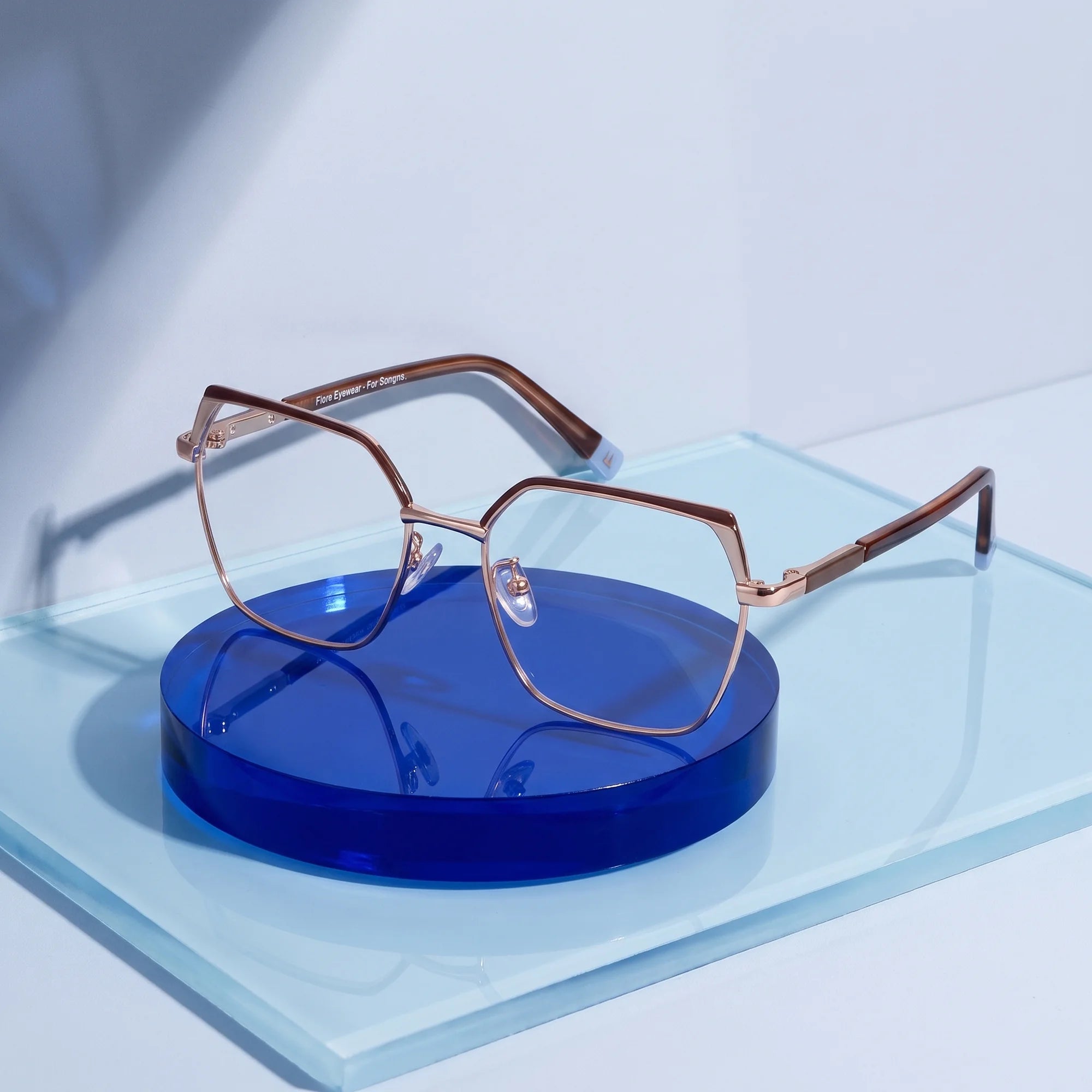 Fiore 3971 eyeglasses in brown gold – on a cobalt acrylic disc in soft daylight