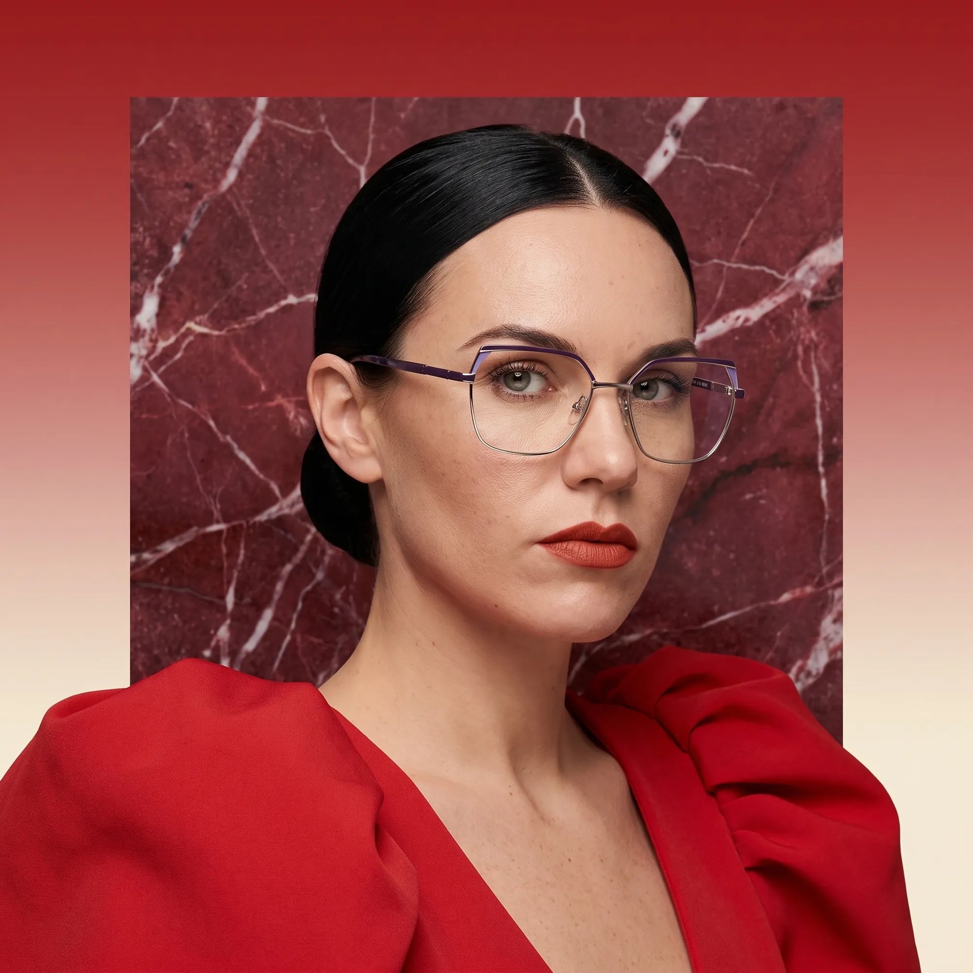 Fiore 3971 eyeglasses in purple silver, worn by a model – campaign portrait, red marble backdrop and draped scarlet dress