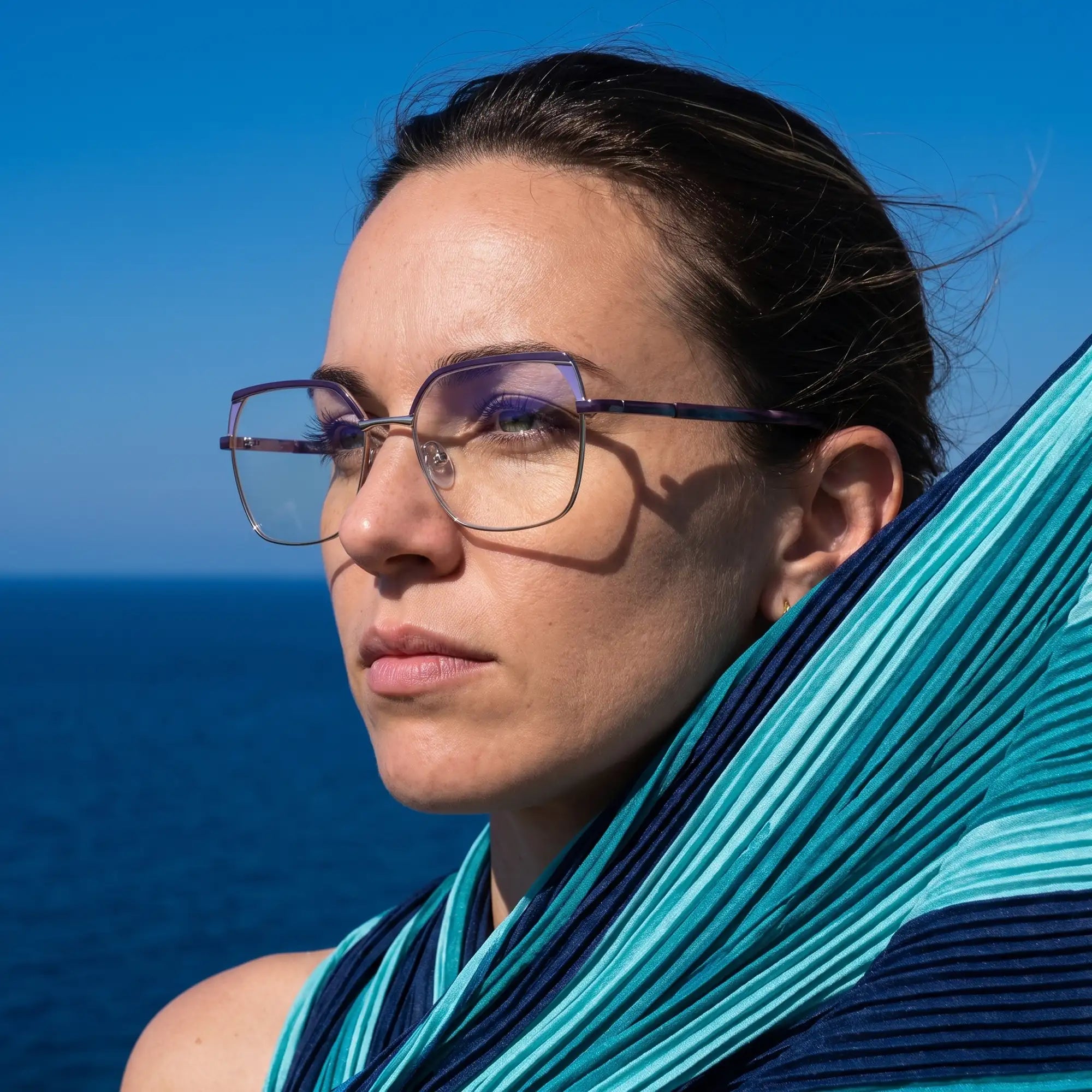 Fiore 3971 eyeglasses in purple silver, worn by a model – campaign portrait, windswept portrait over the deep blue sea
