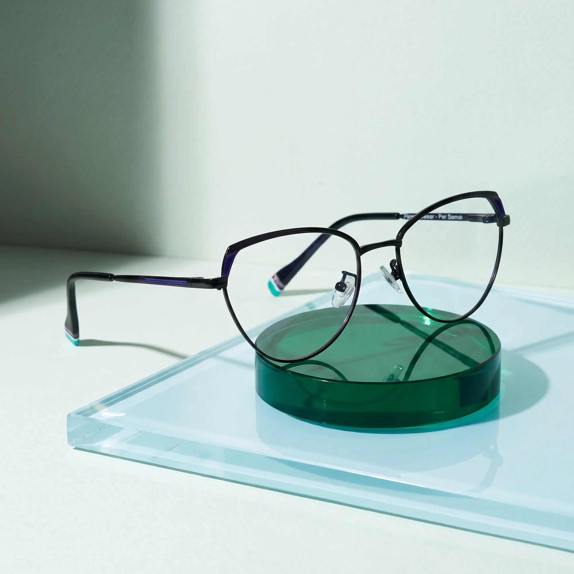 Fiore 3983 eyeglasses in black blue – on a cobalt acrylic disc in soft daylight
