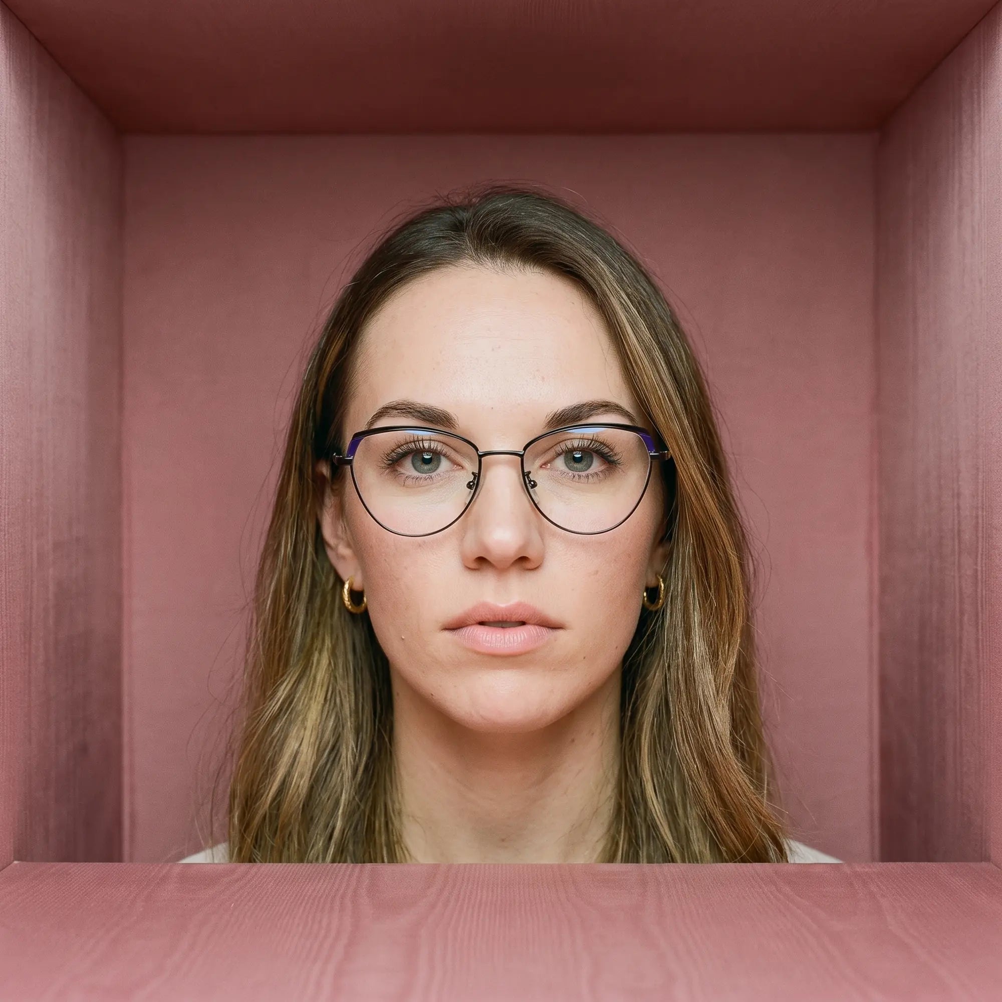Fiore 3983 eyeglasses in black blue, worn by a model – campaign portrait, face framed by rose moire upholstery