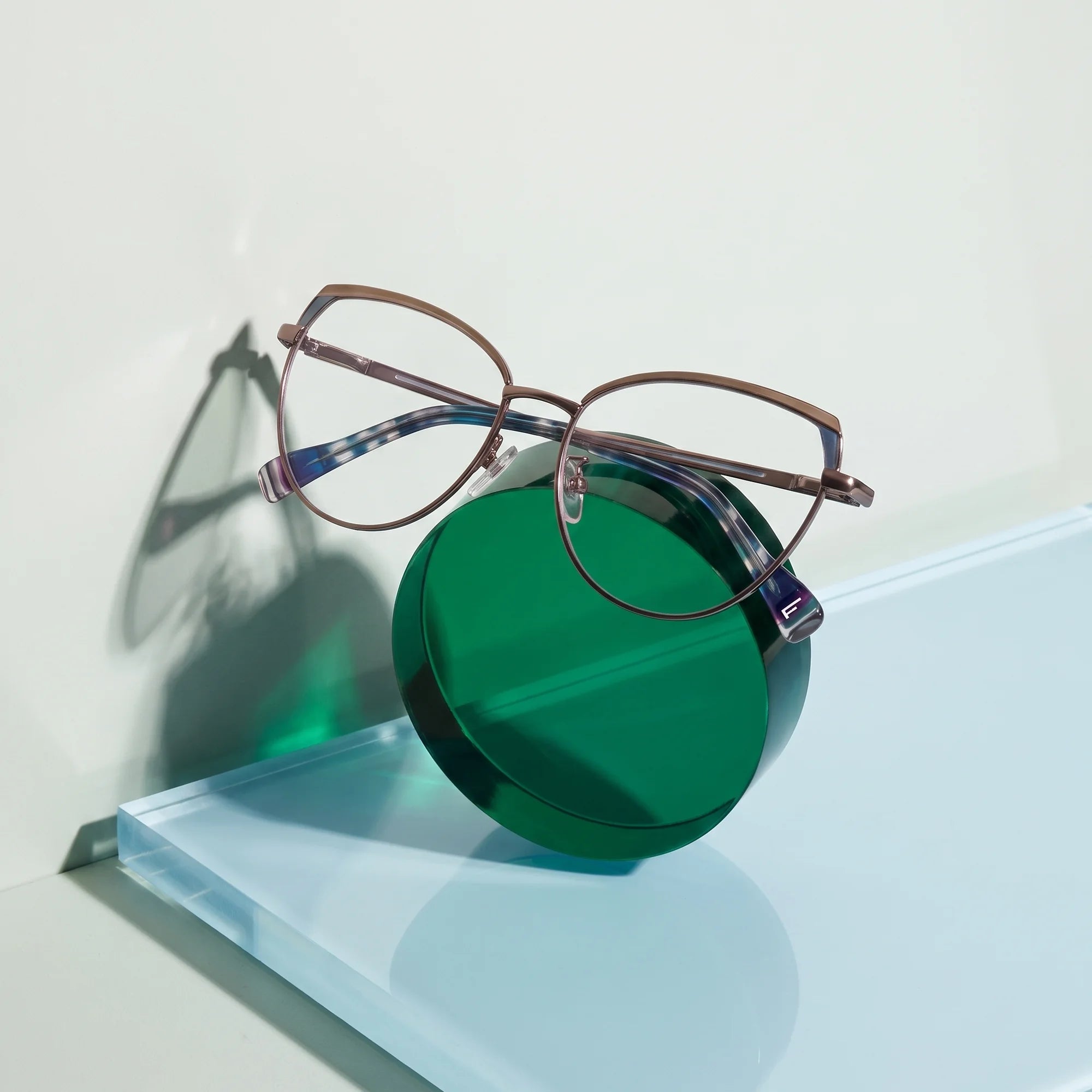 Fiore 3983 eyeglasses in grey gun – on a cobalt acrylic disc in soft daylight