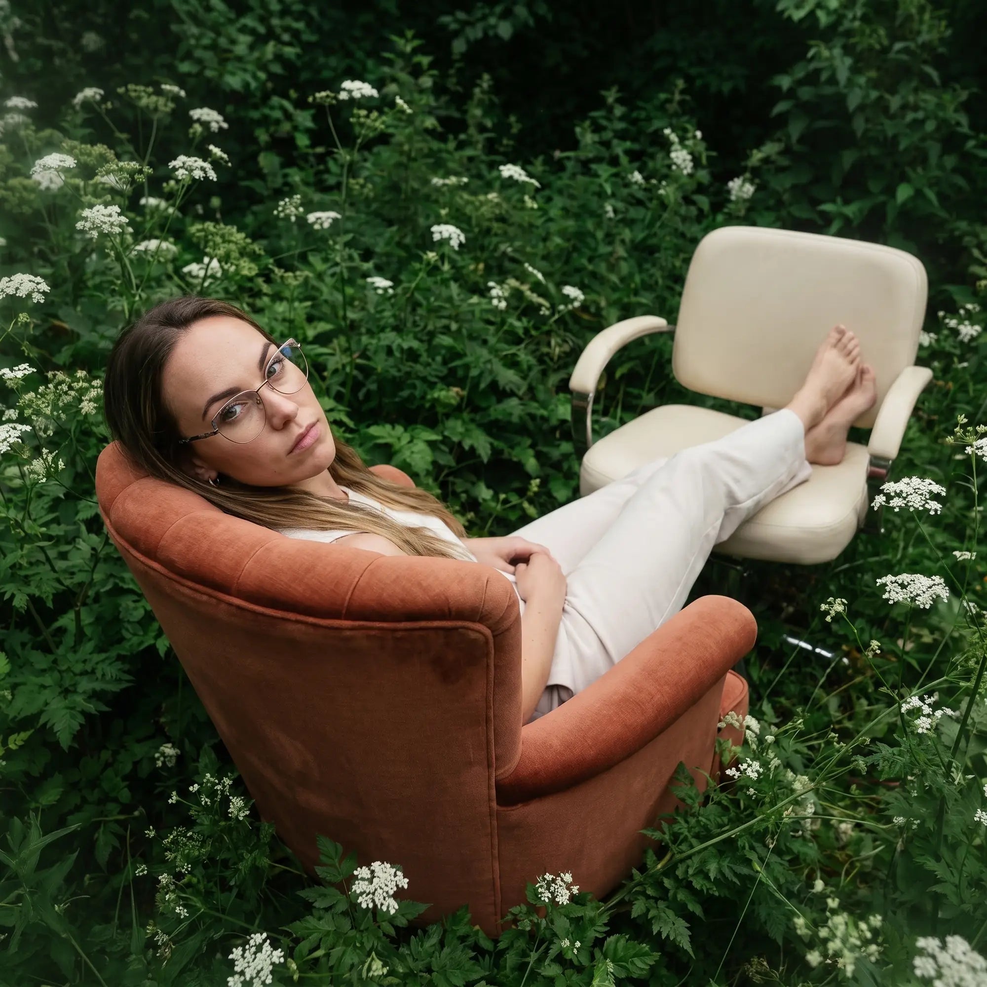 Fiore 3983 eyeglasses in grey gun, worn by a model – campaign portrait, lounging in an armchair in a wildflower meadow