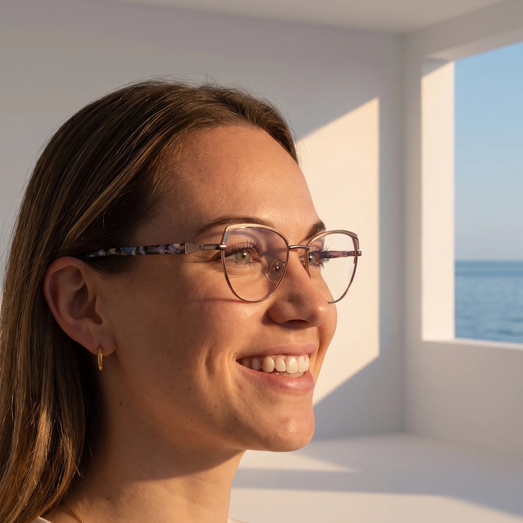 Fiore 3983 eyeglasses in grey gun, worn by a model – campaign portrait, smiling at a bright window over the sea