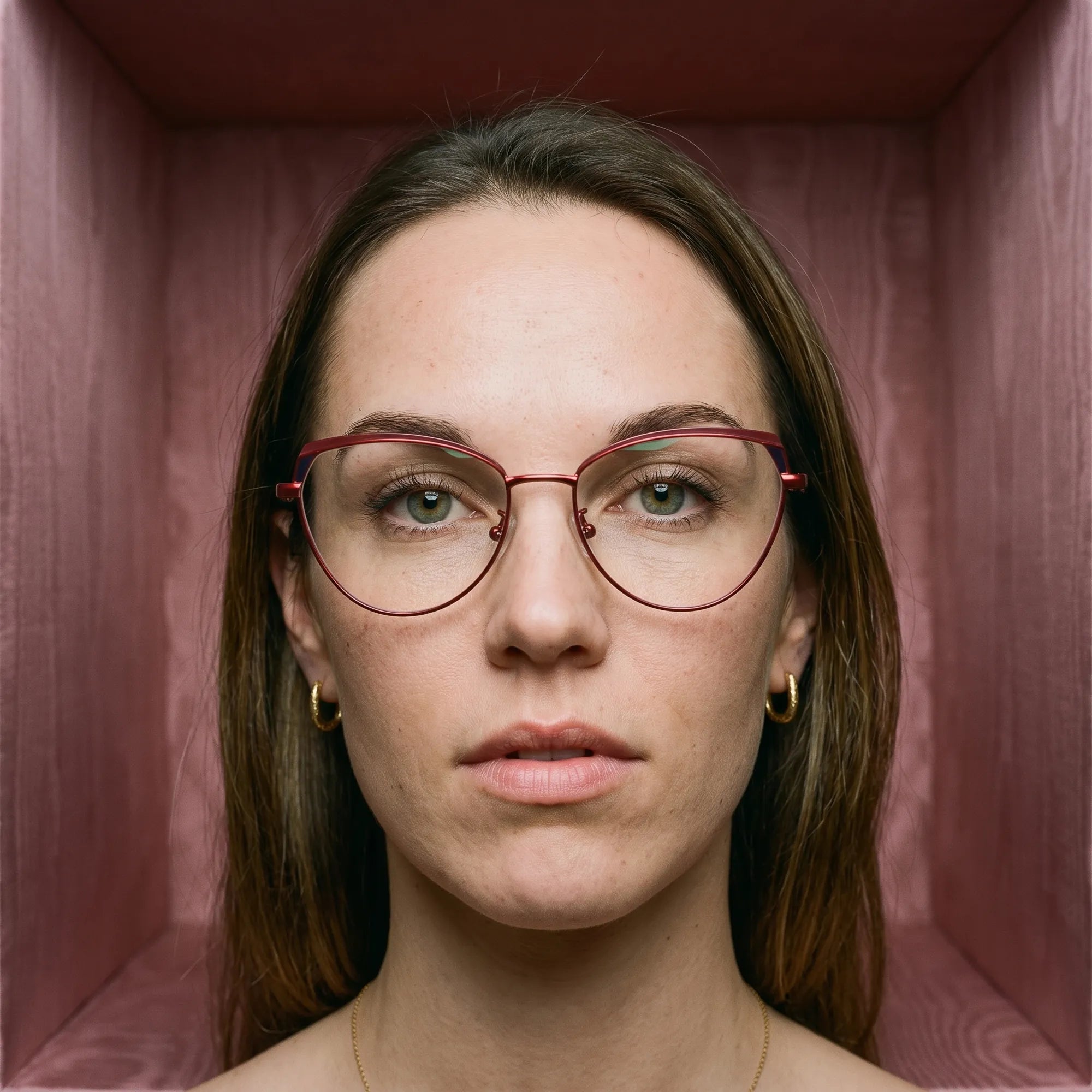 Fiore 3983 eyeglasses in red black, worn by a model – campaign portrait, face framed by rose moire upholstery