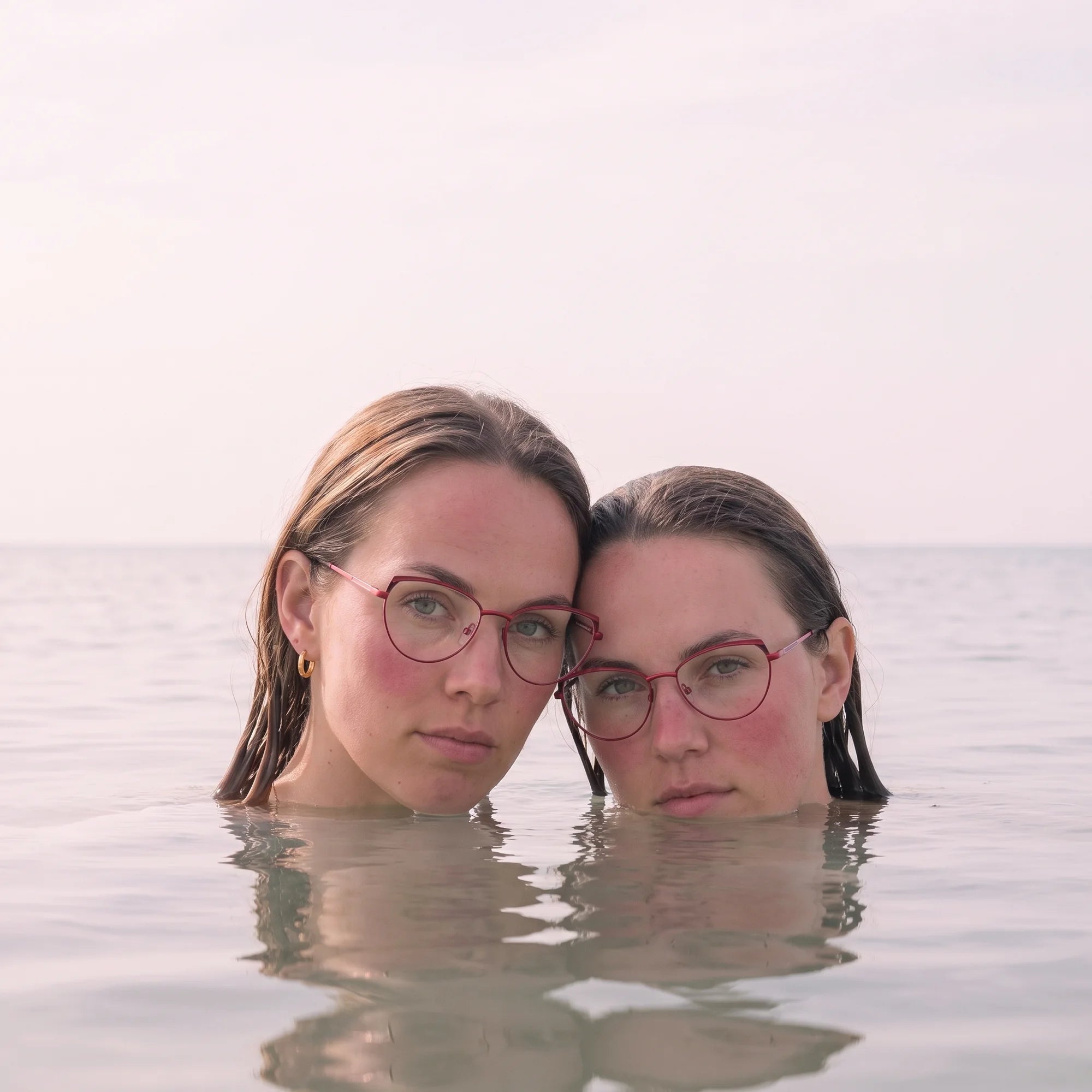 Fiore 3983 eyeglasses in red black, worn by a model – campaign portrait, wet-hair portrait in a calm summer sea