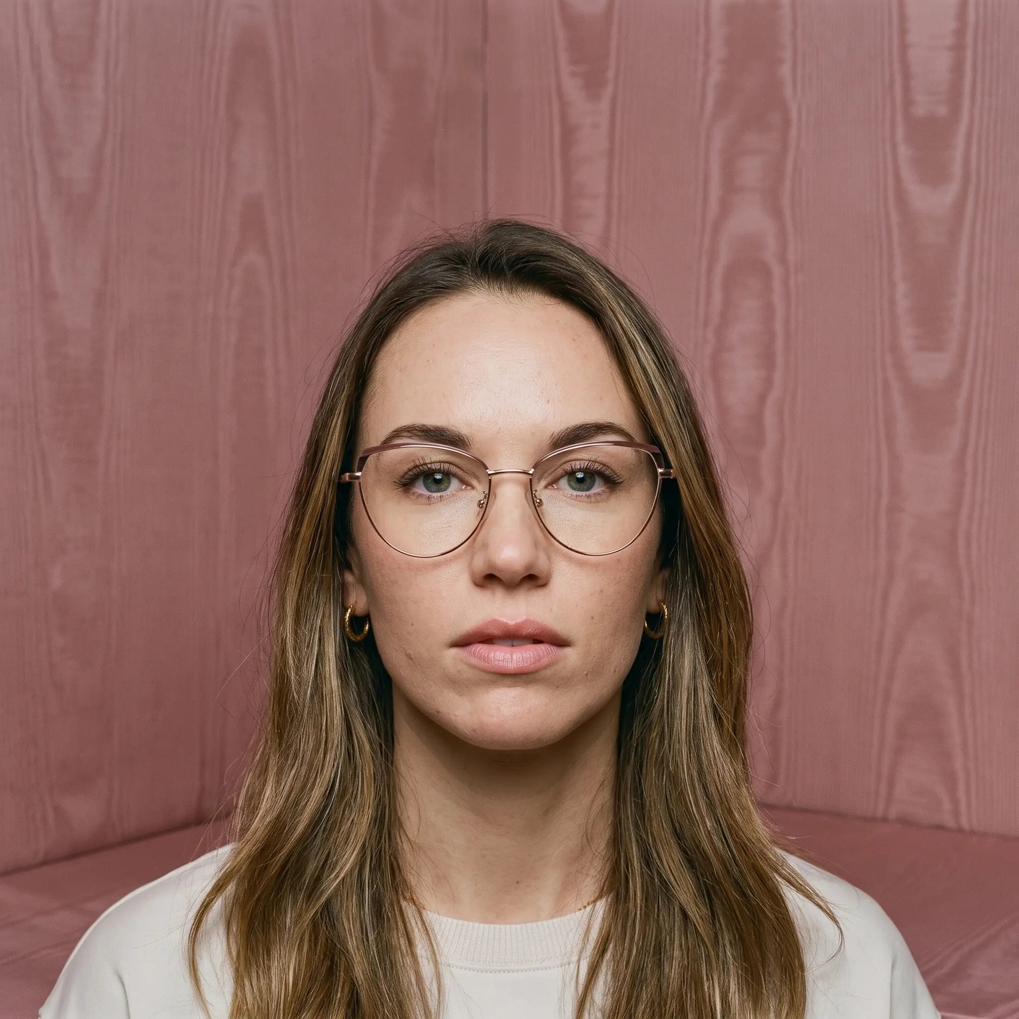 Fiore 3983 eyeglasses in brown gold, worn by a model – campaign portrait, face framed by rose moire upholstery