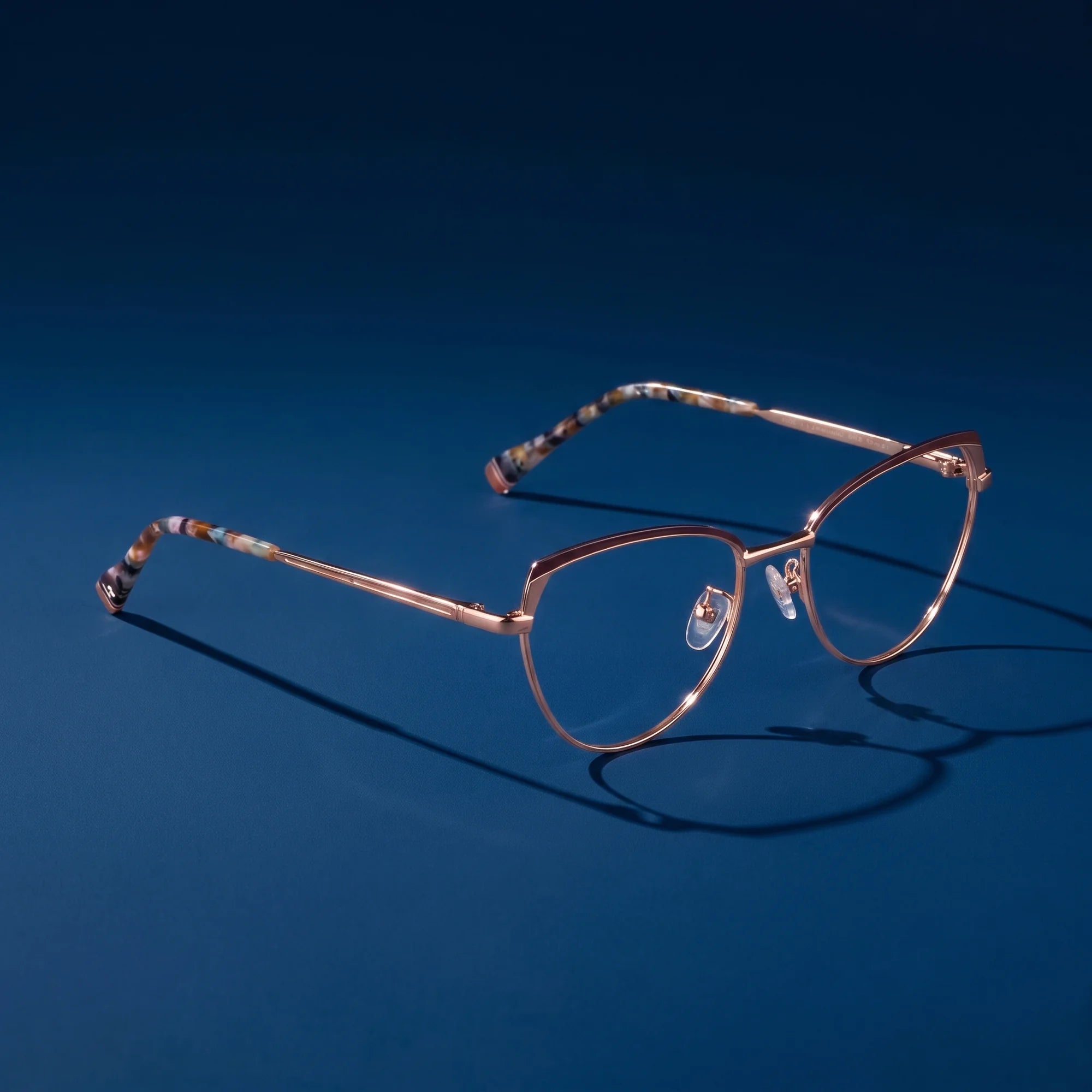 Fiore 3983 eyeglasses in brown gold – hero still life against a deep midnight blue backdrop