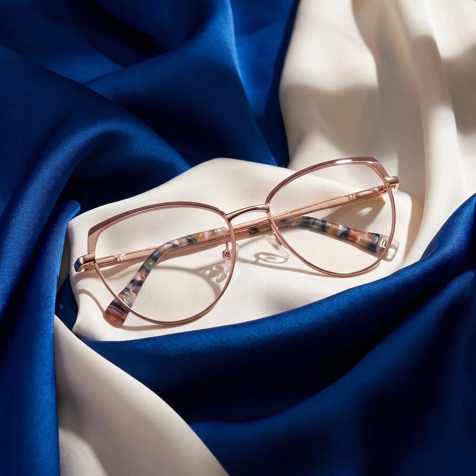 Fiore 3983 eyeglasses in brown gold – resting on draped cobalt and ivory silk