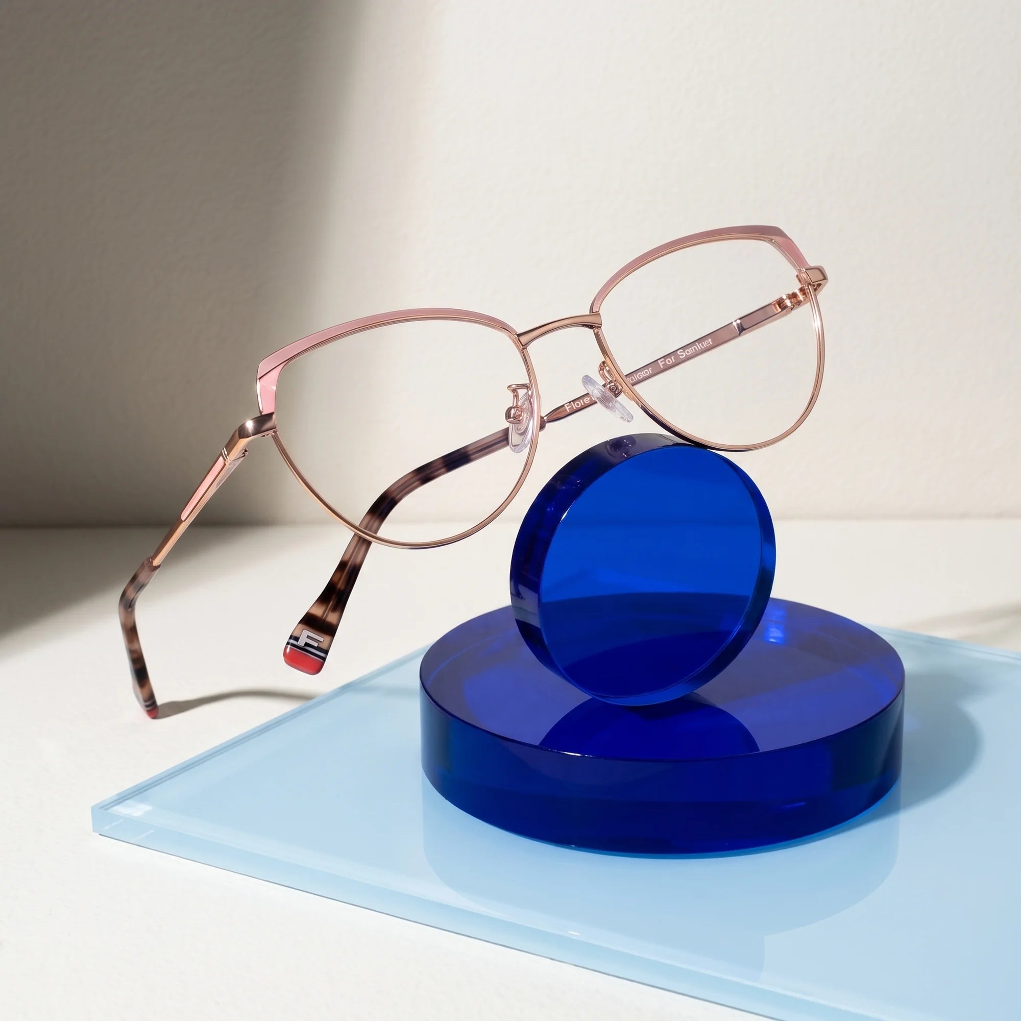 Fiore 3983 eyeglasses in pink gold – on a cobalt acrylic disc in soft daylight