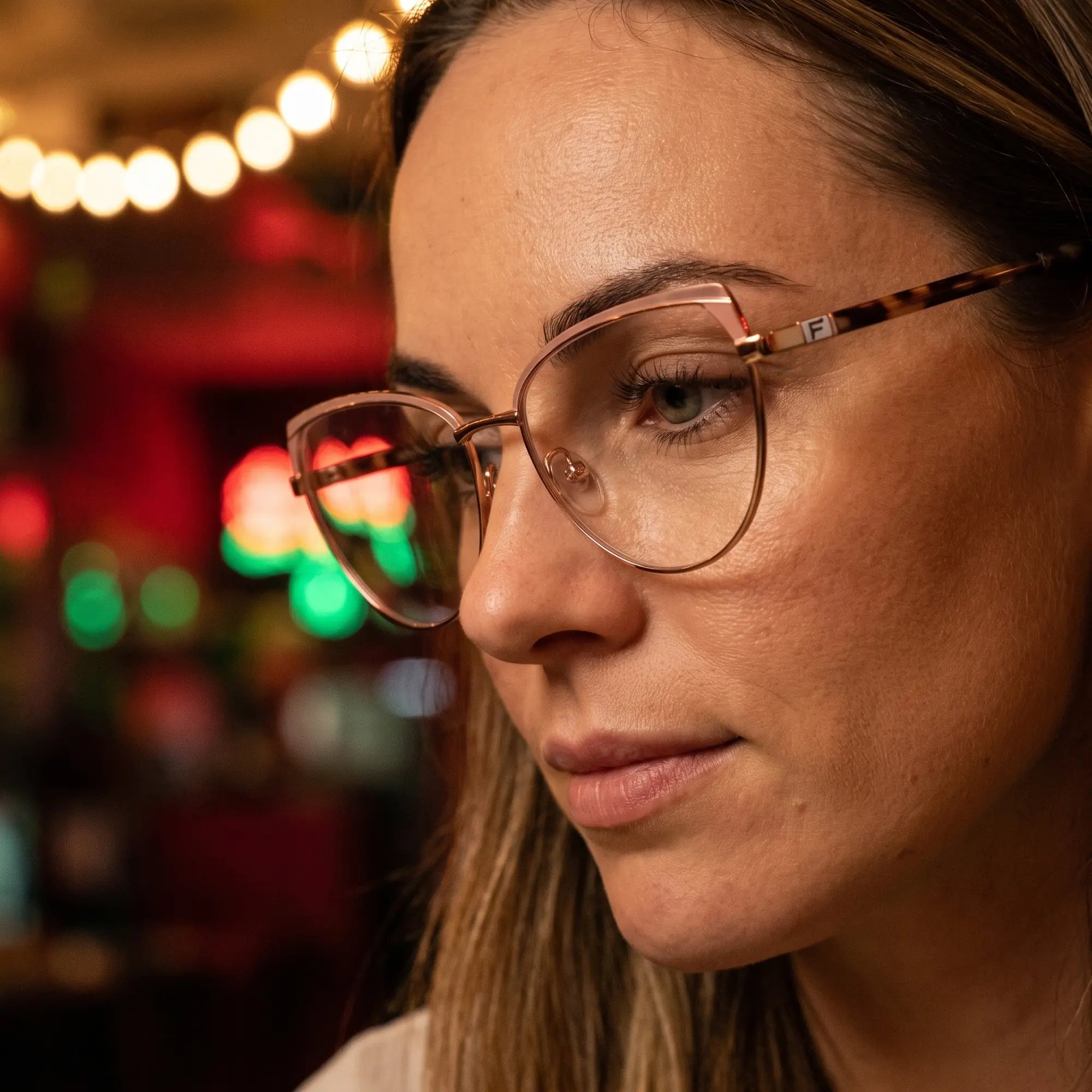 Fiore 3983 eyeglasses in pink gold, worn by a model – campaign portrait, candid portrait in neon-lit evening glow