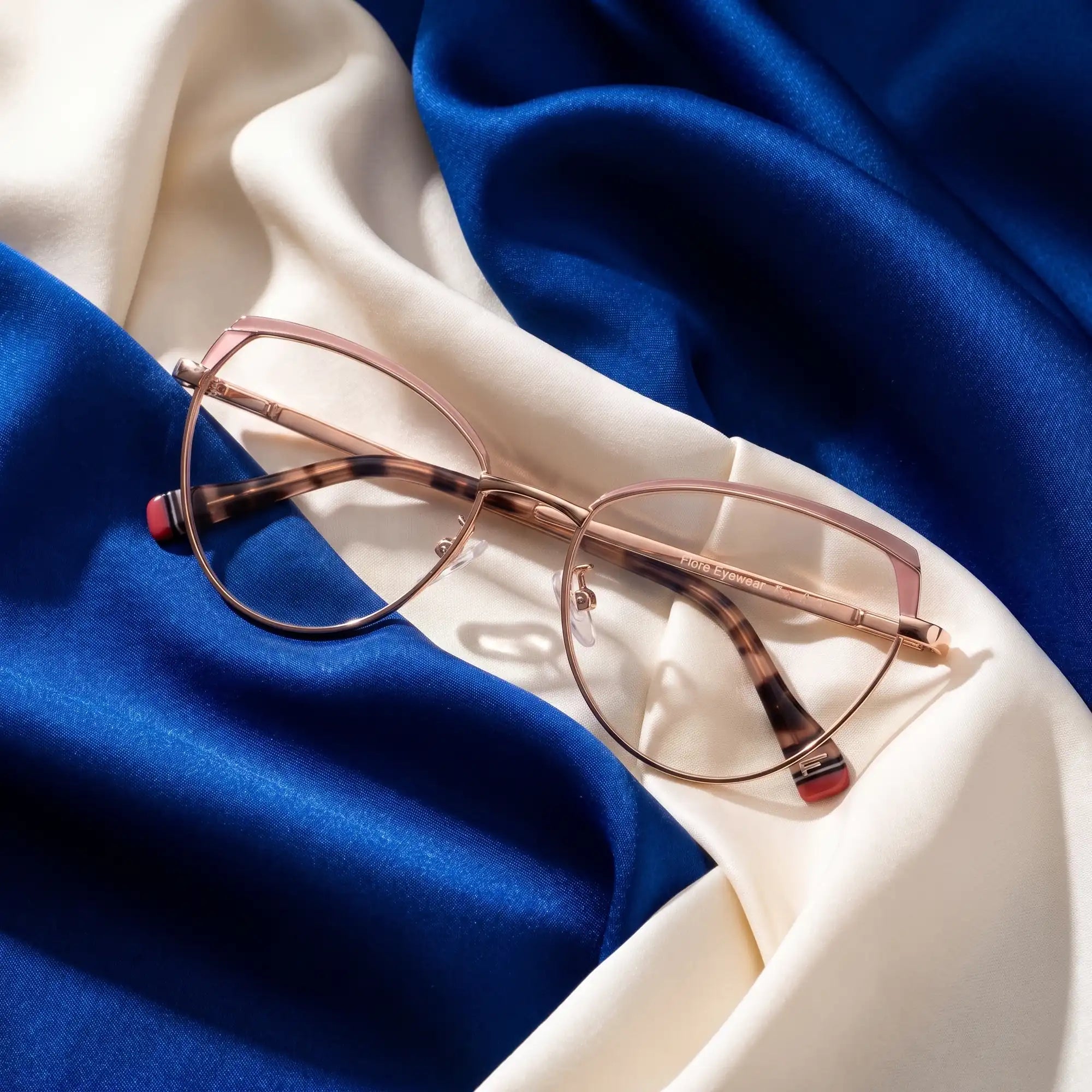 Fiore 3983 eyeglasses in pink gold – resting on draped cobalt and ivory silk