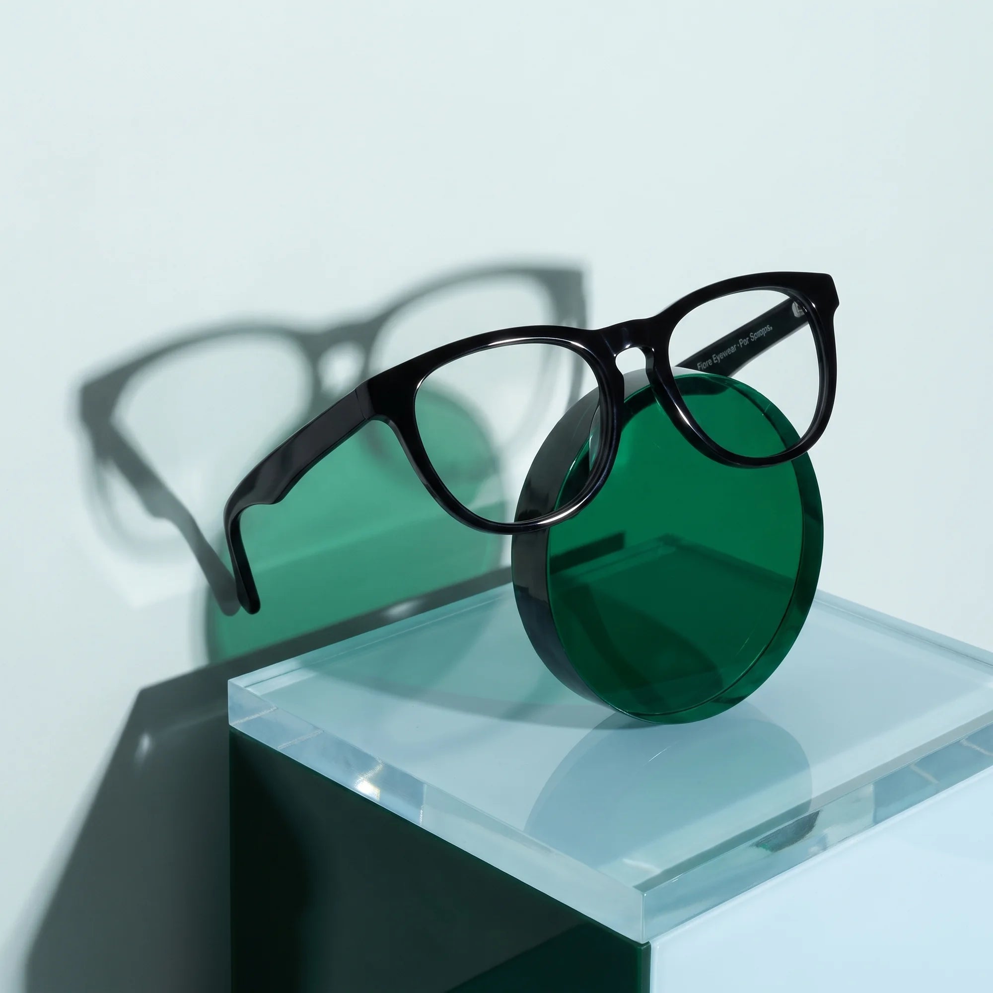 Fiore 4488 eyeglasses in black – on a cobalt acrylic disc in soft daylight