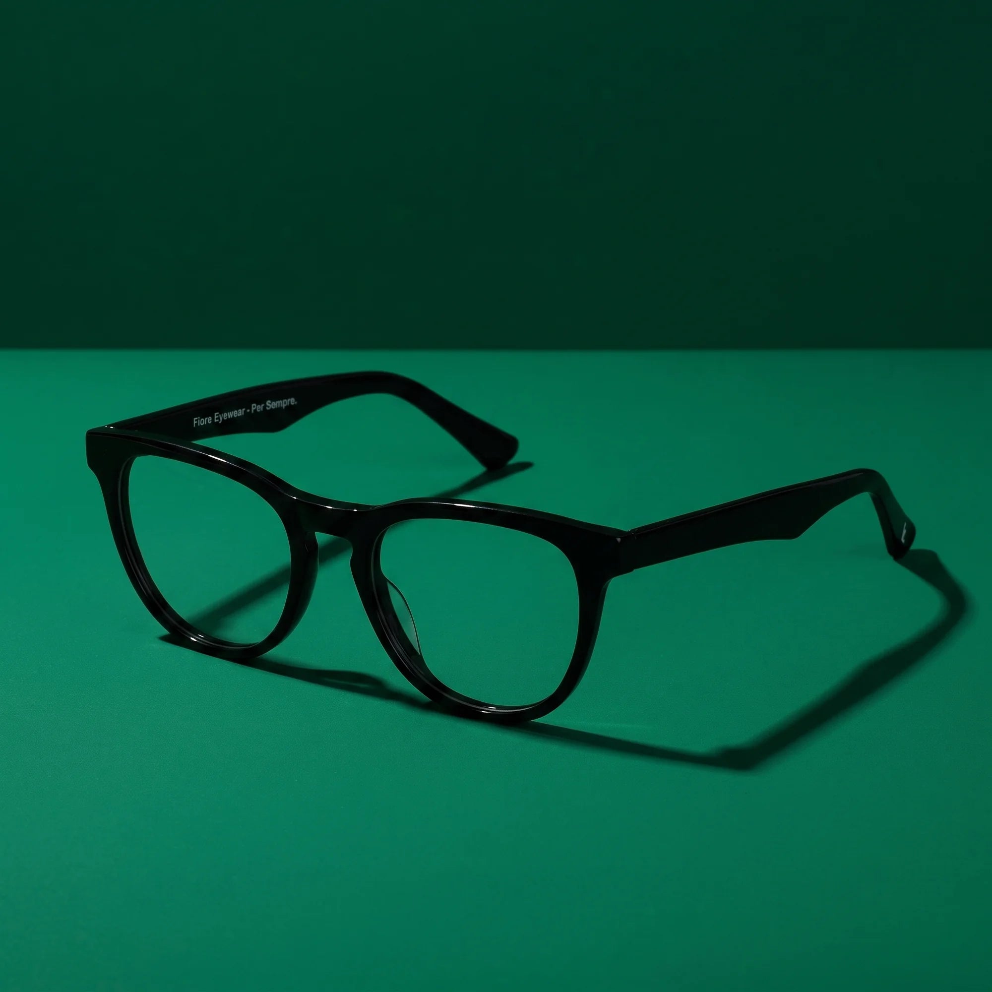 Fiore 4488 eyeglasses in black – still life on a seamless emerald studio backdrop
