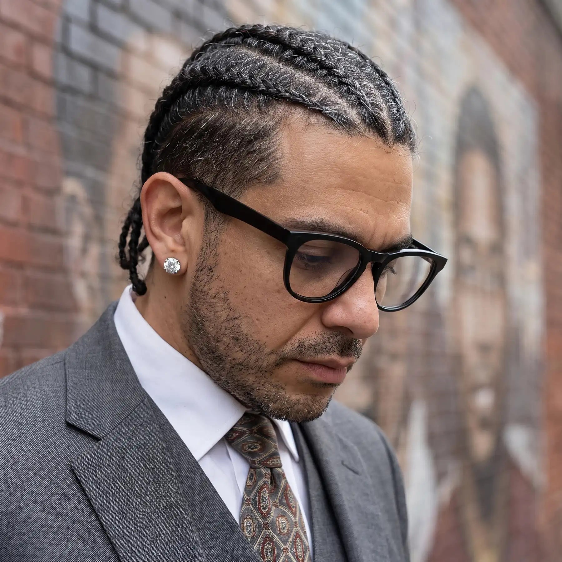Fiore 4488 eyeglasses in black, worn by a model – campaign portrait, pensive portrait against a painted brick mural