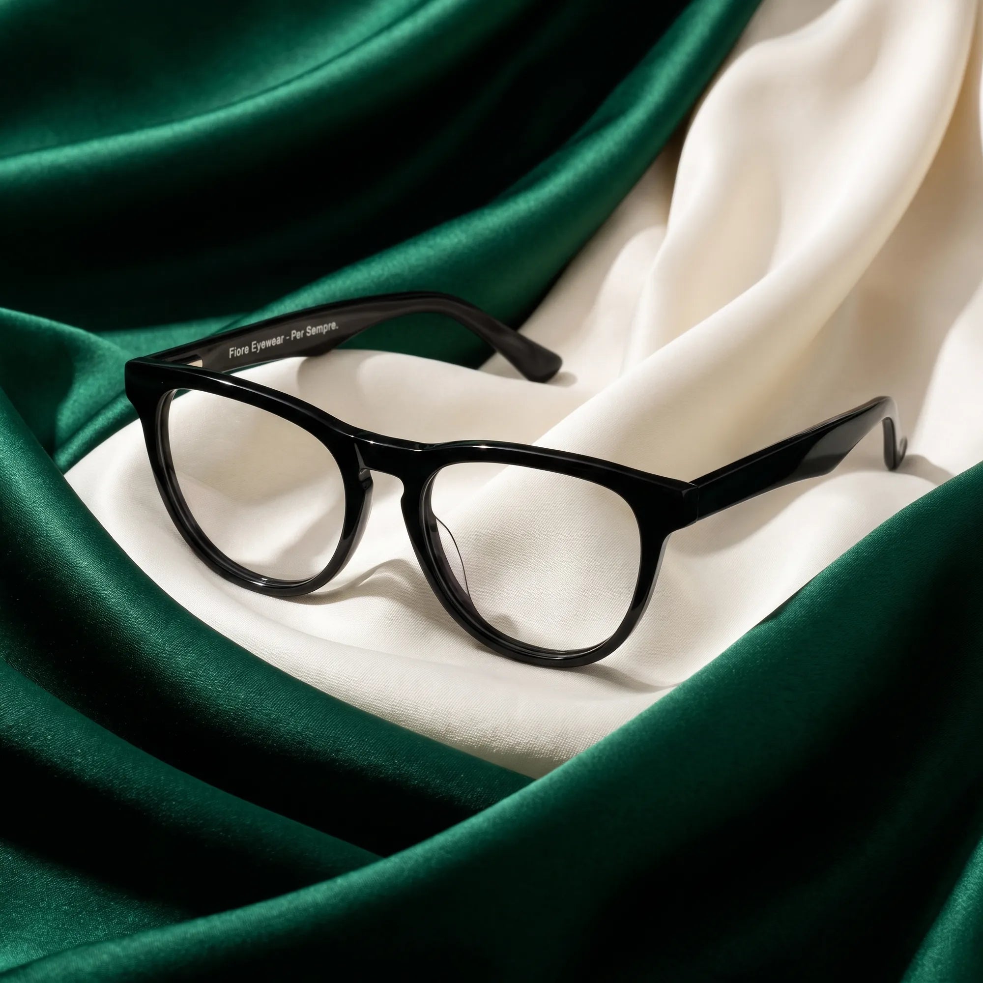 Fiore 4488 eyeglasses in black – resting on draped emerald and ivory silk