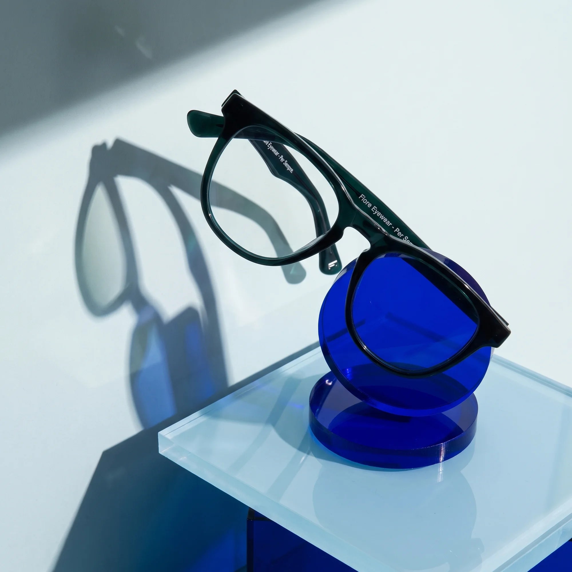 Fiore 4488 eyeglasses in green – on a cobalt acrylic disc in soft daylight