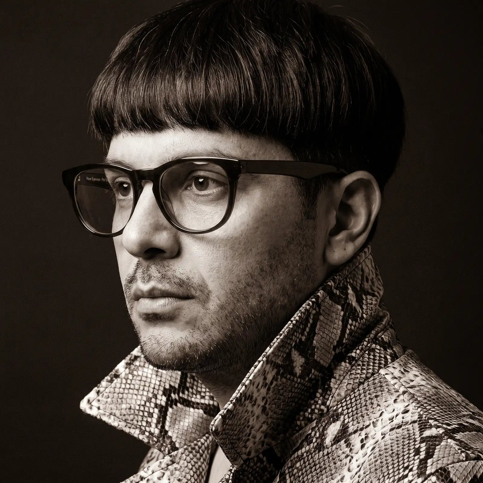 Fiore 4488 eyeglasses in green, worn by a model – campaign portrait, monochrome studio portrait, red graphic accents
