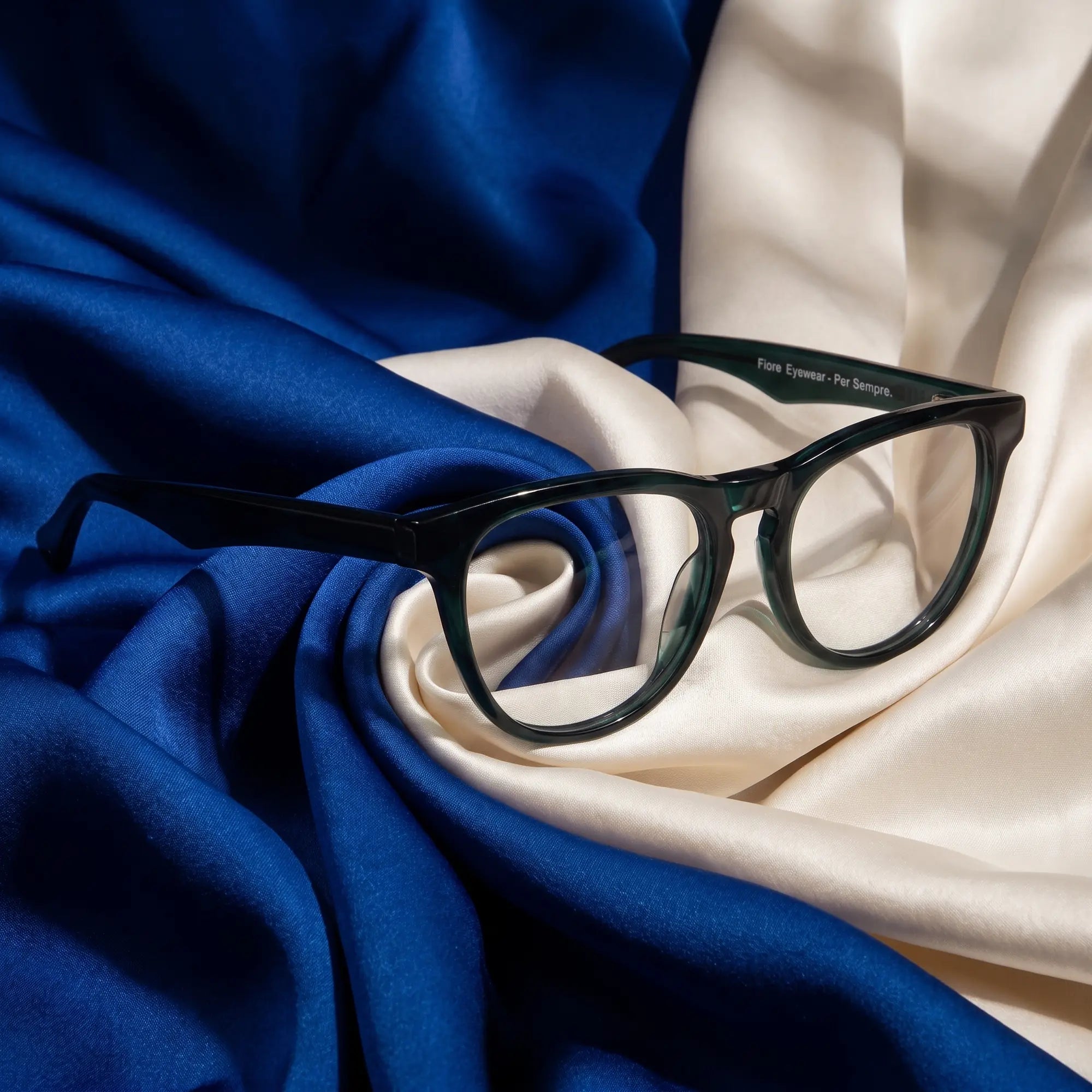 Fiore 4488 eyeglasses in green – resting on draped cobalt and ivory silk
