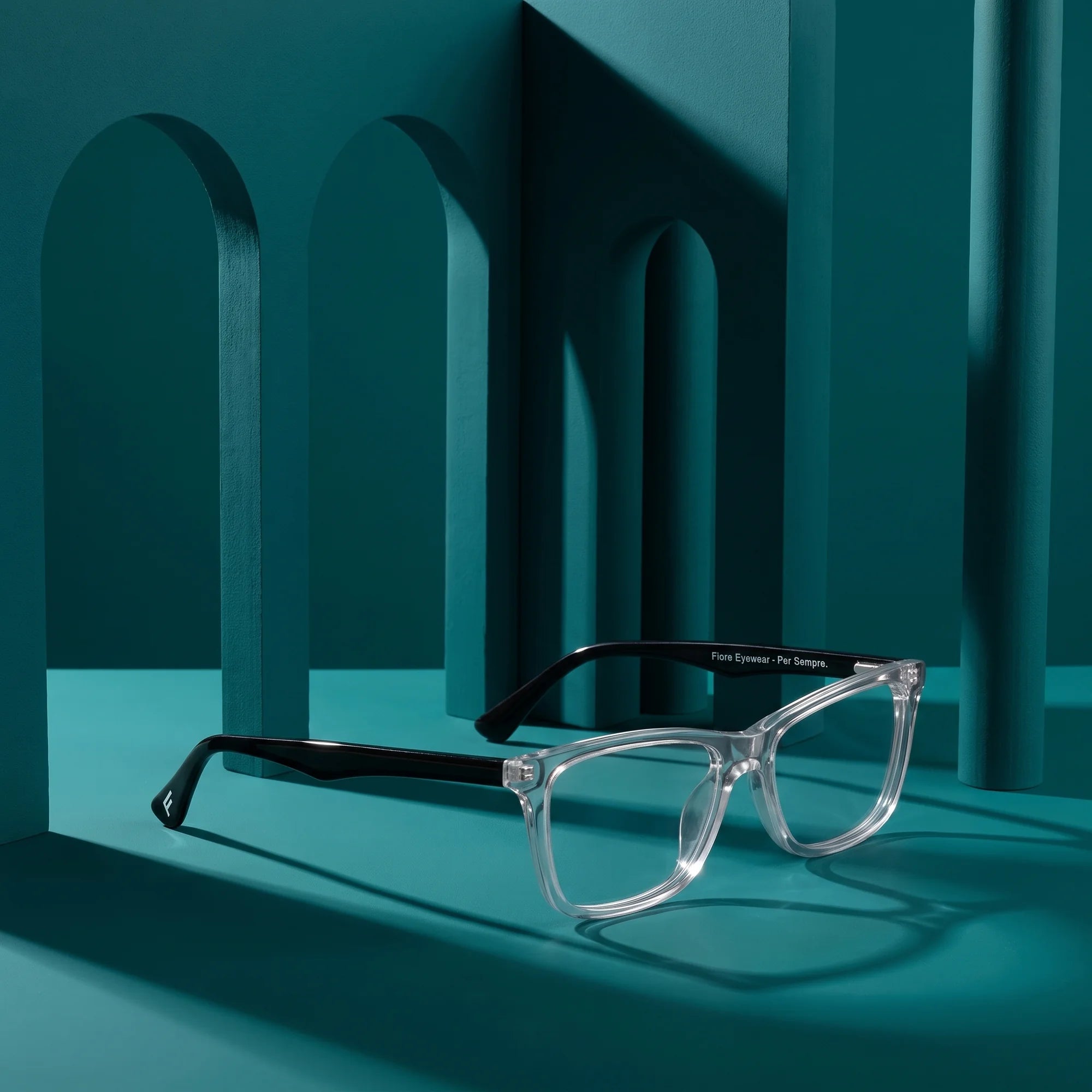 Fiore 5228 eyeglasses in transparent – staged on a sculptural teal architecture set