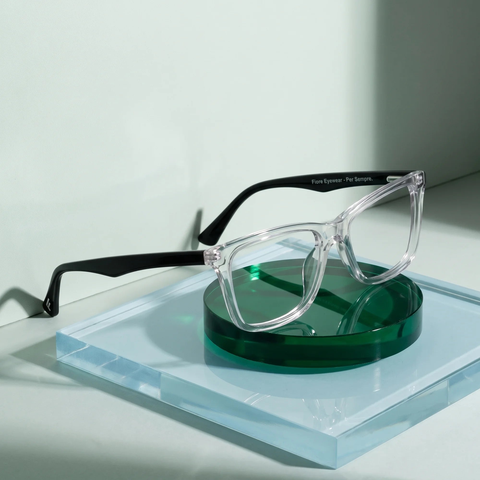 Fiore 5228 eyeglasses in transparent – on a cobalt acrylic disc in soft daylight