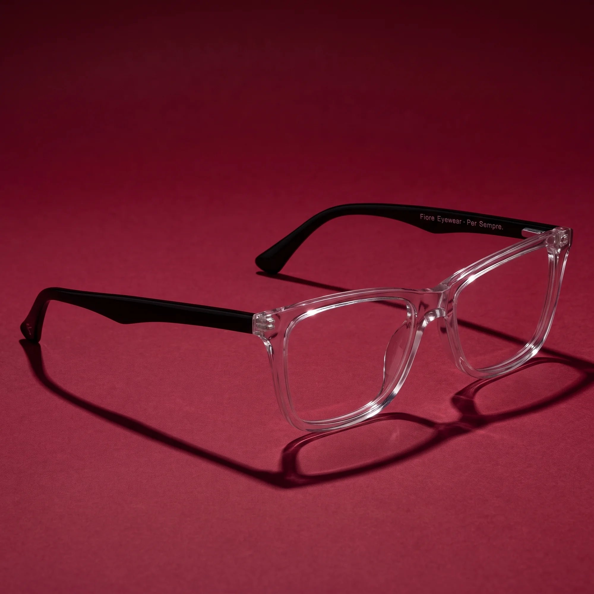 Fiore 5228 eyeglasses in transparent – editorial still life on a saturated burgundy set