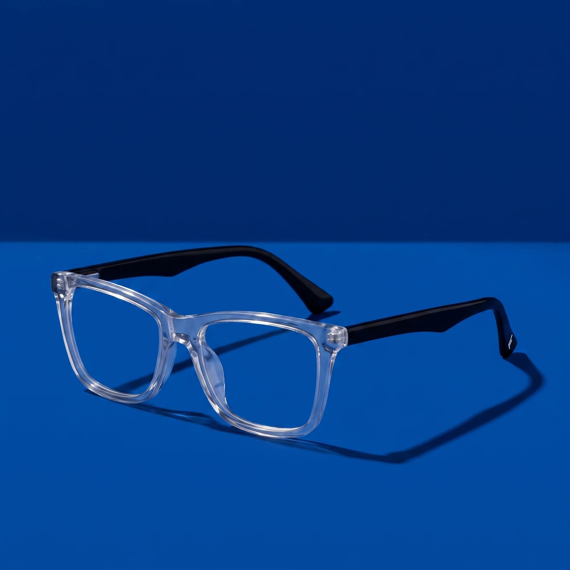 Fiore 5228 eyeglasses in transparent – hero still life against a deep cobalt backdrop