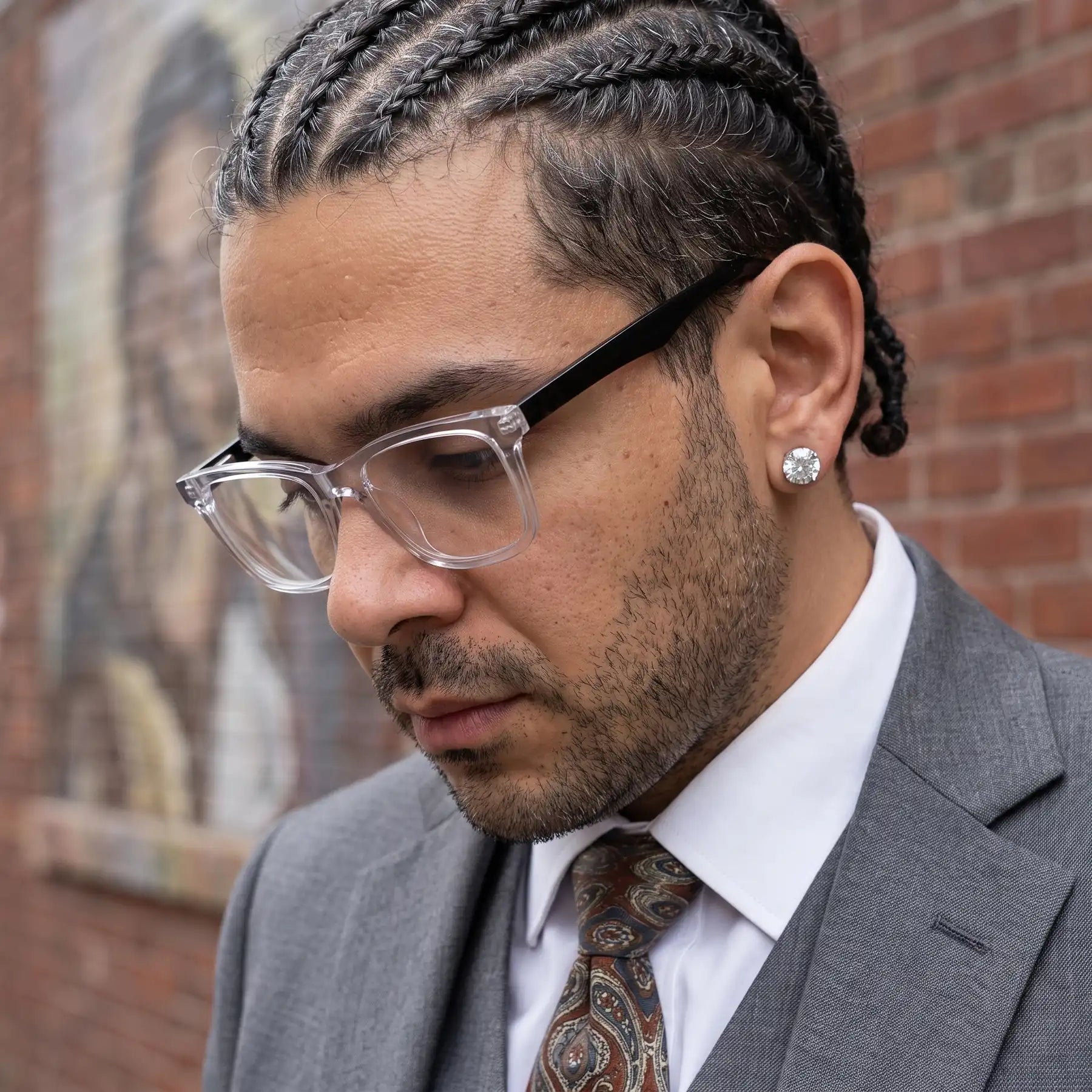Fiore 5228 eyeglasses in transparent, worn by a model – campaign portrait, pensive portrait against a painted brick mural