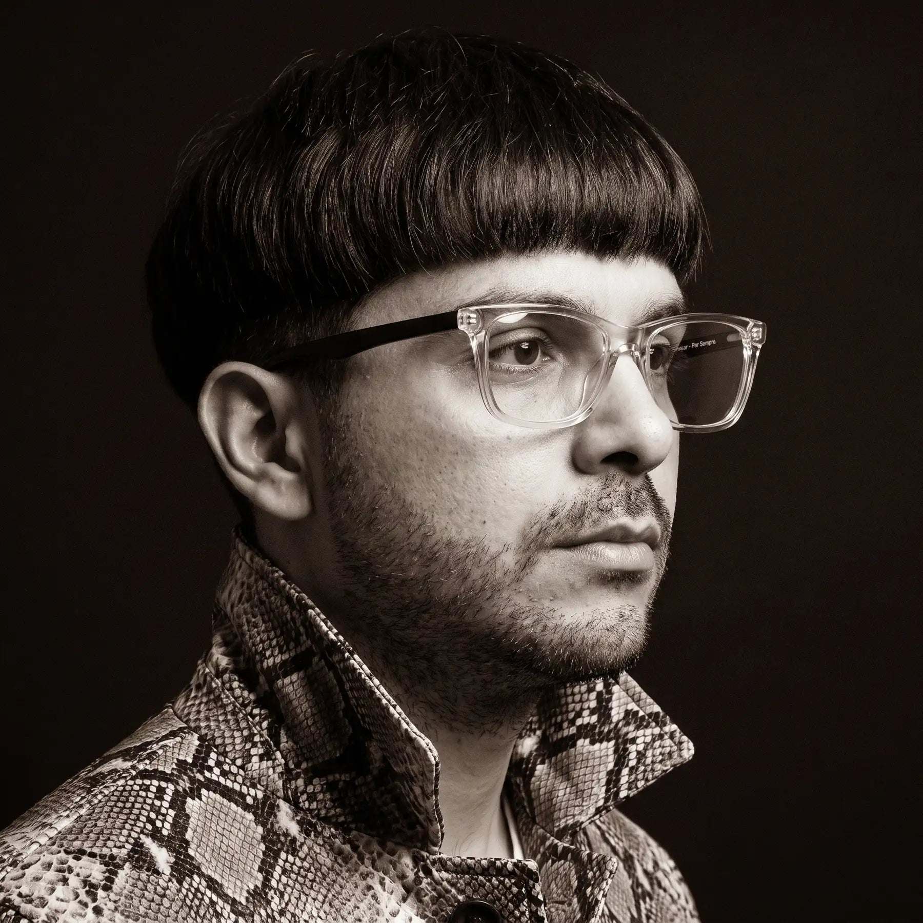 Fiore 5228 eyeglasses in transparent, worn by a model – campaign portrait, monochrome studio portrait, red graphic accents