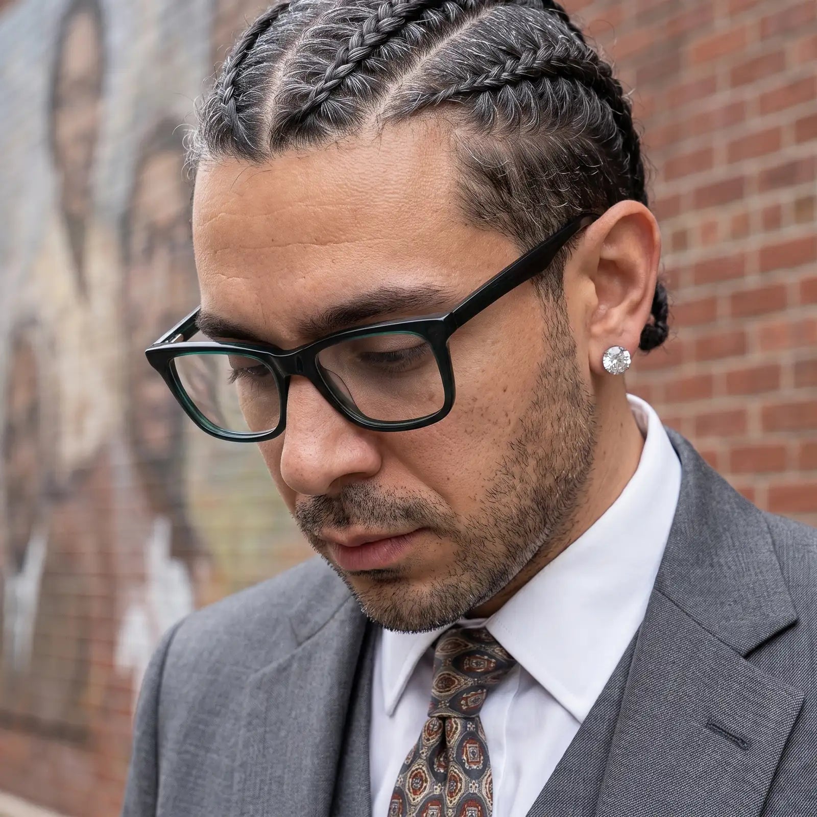 Fiore 5228 eyeglasses in green, worn by a model – campaign portrait, pensive portrait against a painted brick mural