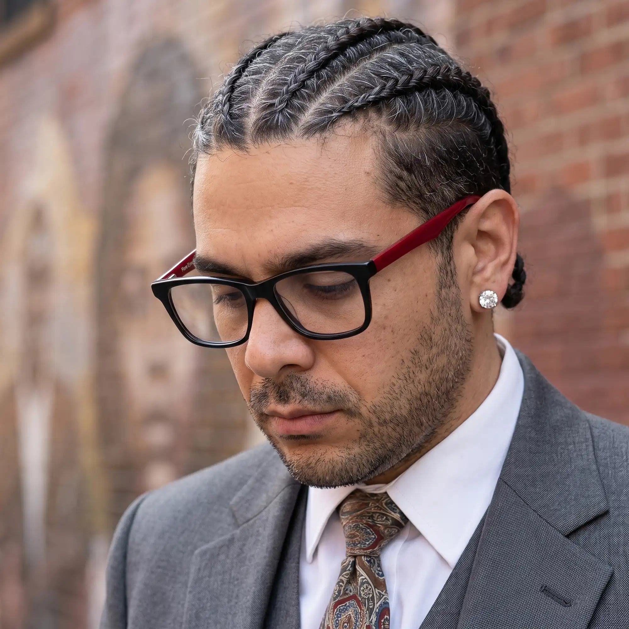 Fiore 5228 eyeglasses in black, worn by a model – campaign portrait, pensive portrait against a painted brick mural