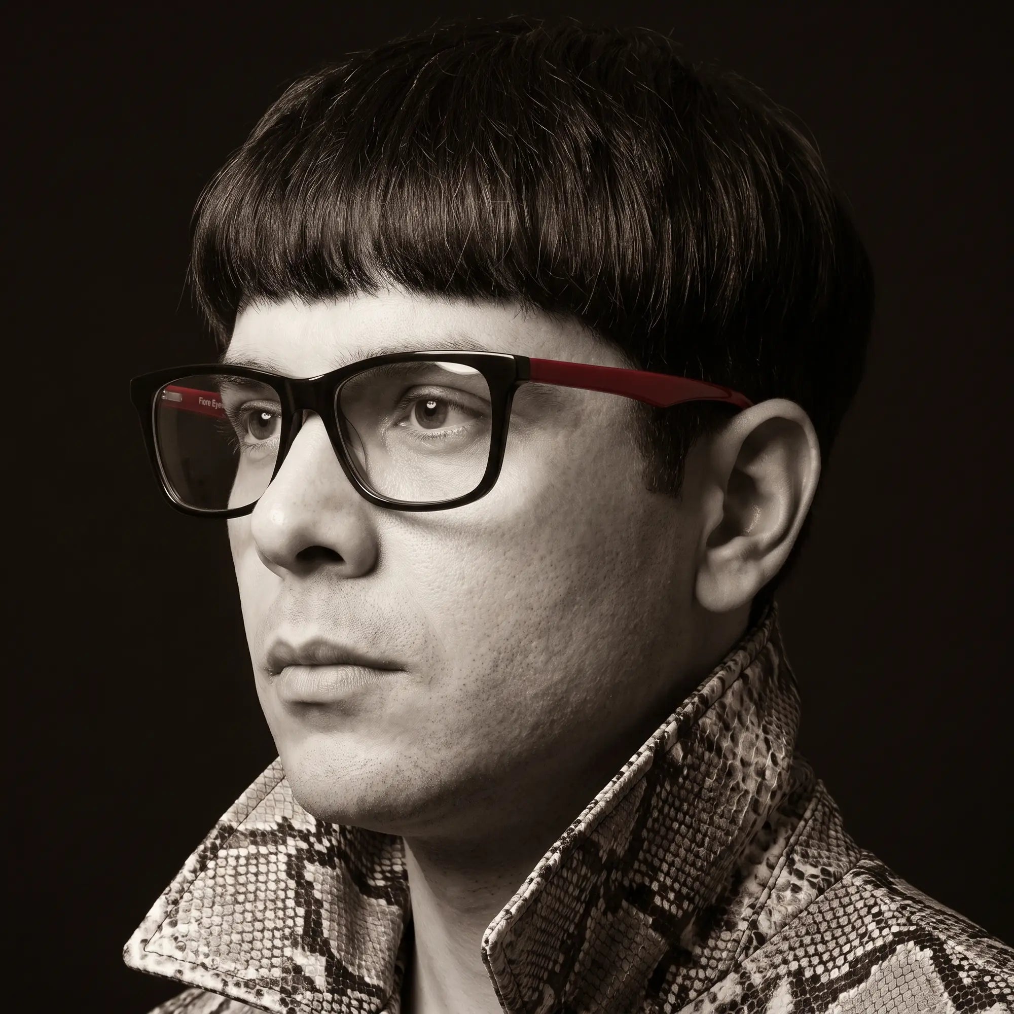 Fiore 5228 eyeglasses in black, worn by a model – campaign portrait, monochrome studio portrait, red graphic accents