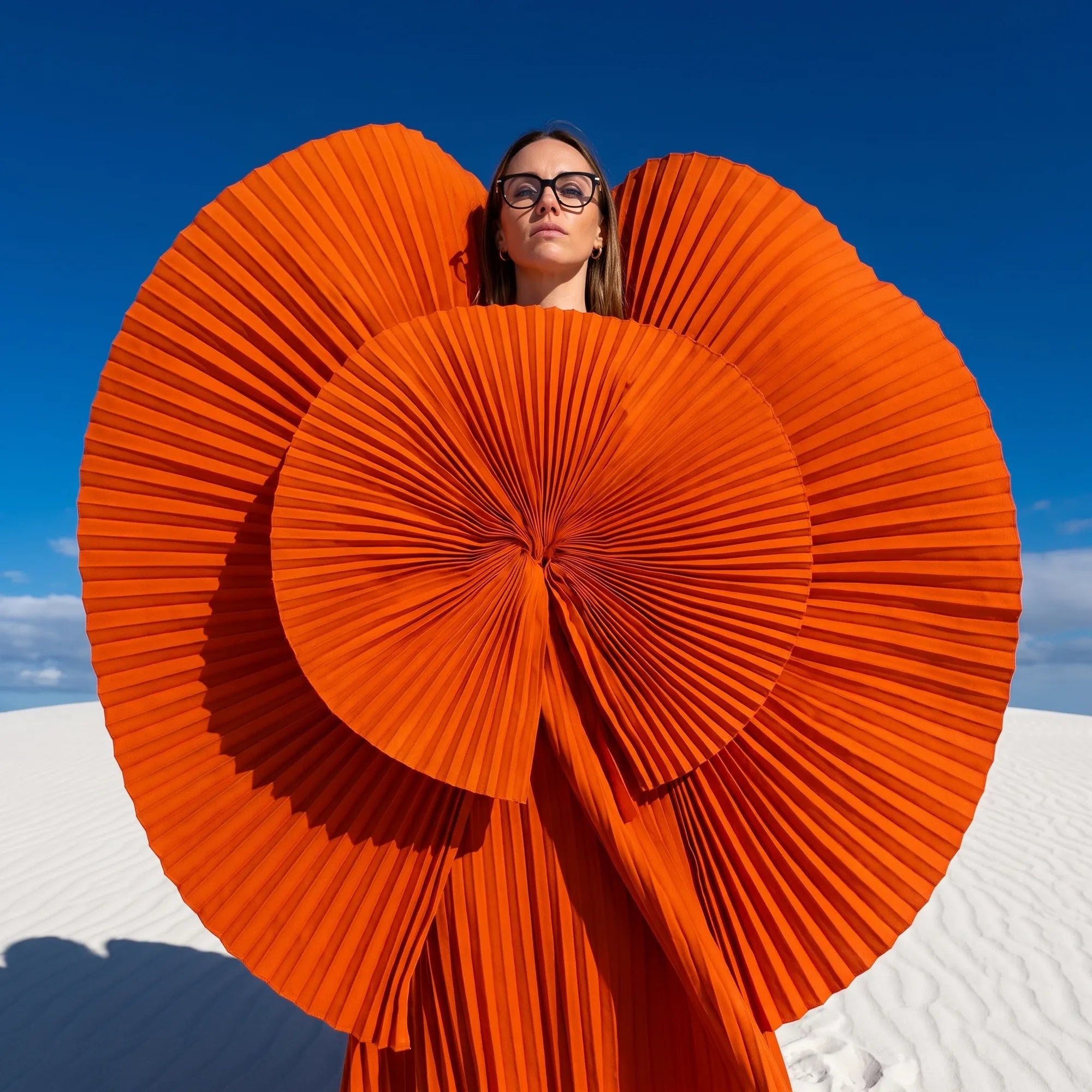 Fiore 5409 eyeglasses in black, worn by a model – campaign portrait, sculptural orange pleated fan on white dunes