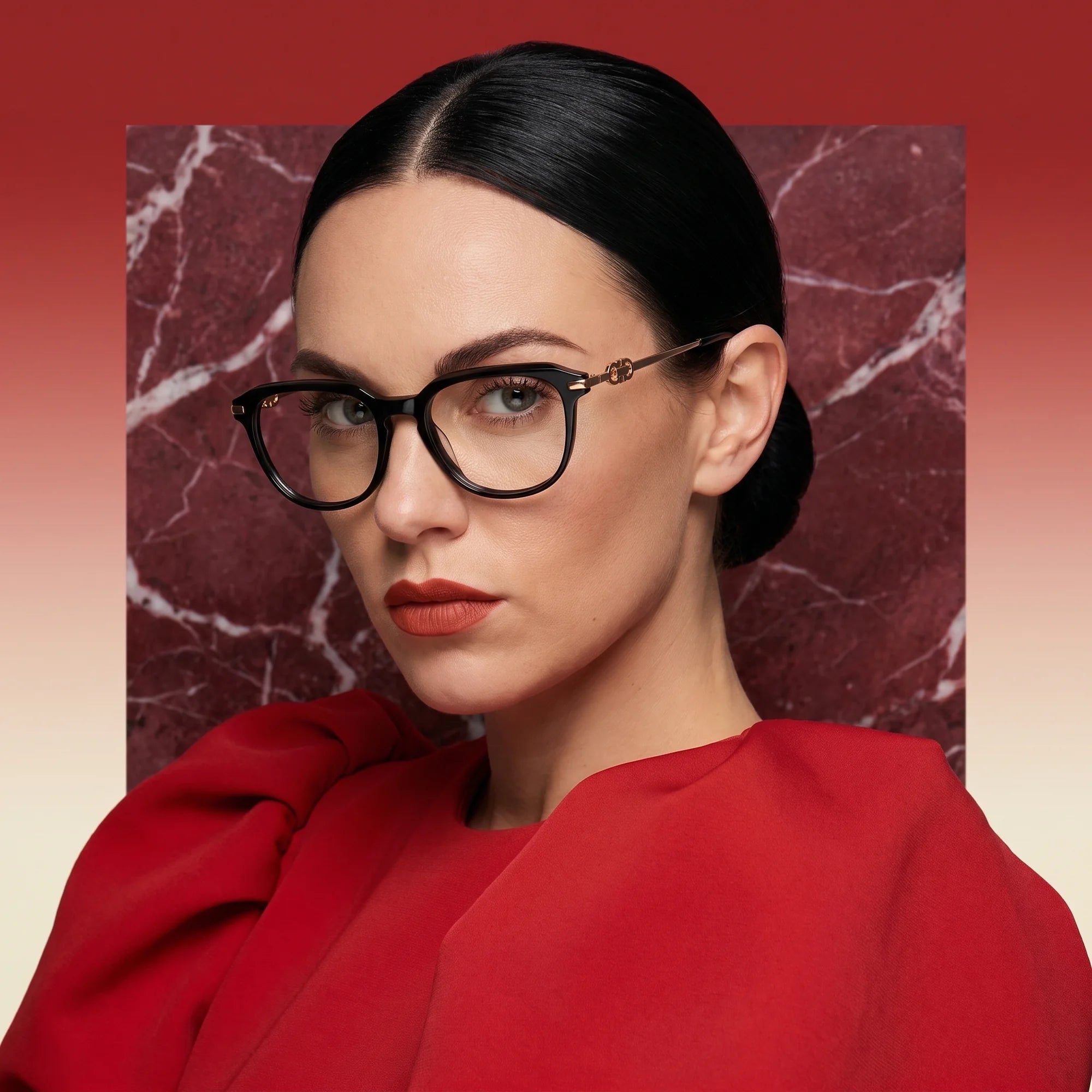 Fiore 5409 eyeglasses in black, worn by a model – campaign portrait, red marble backdrop and draped scarlet dress