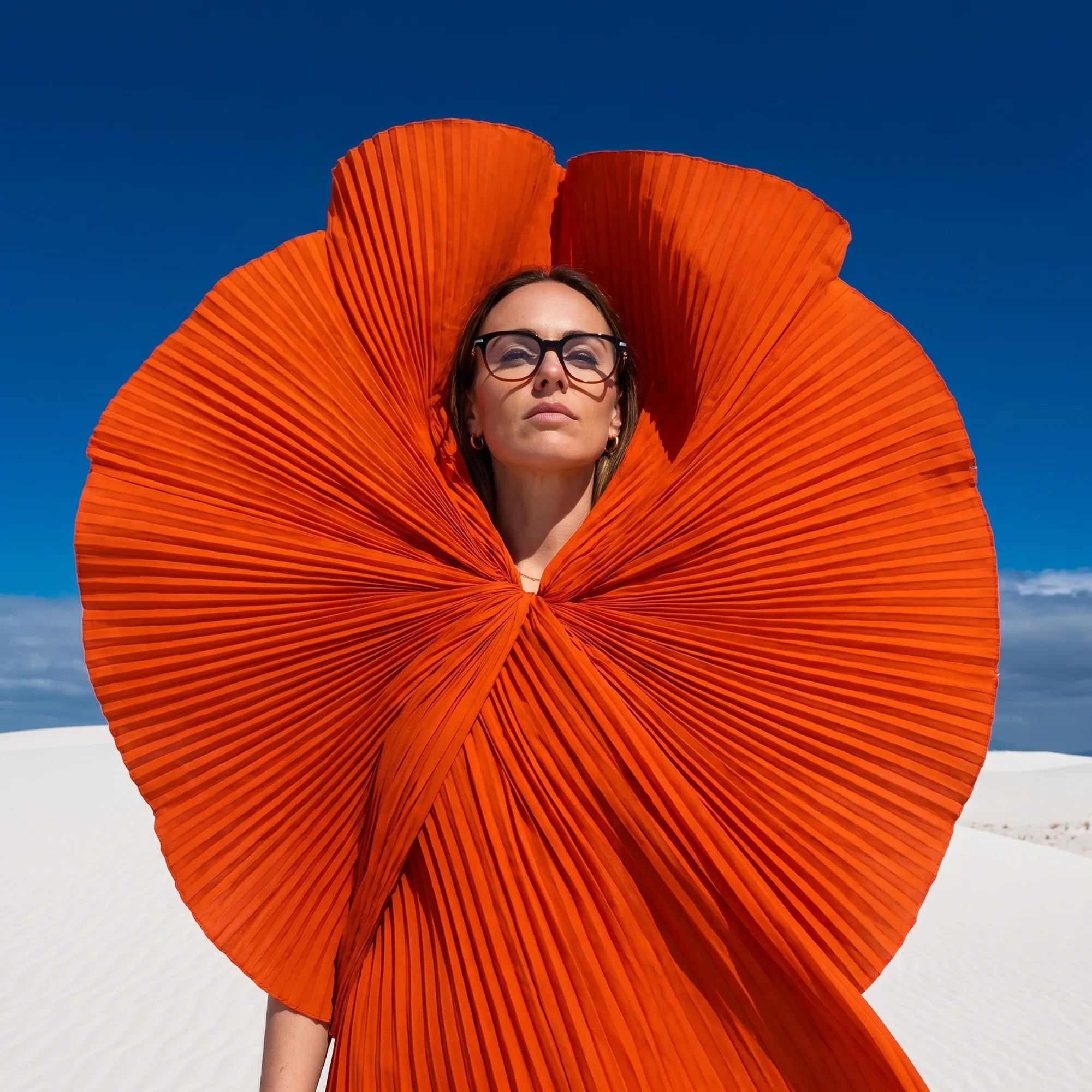 Fiore 5409 eyeglasses in black brown, worn by a model – campaign portrait, sculptural orange pleated fan on white dunes