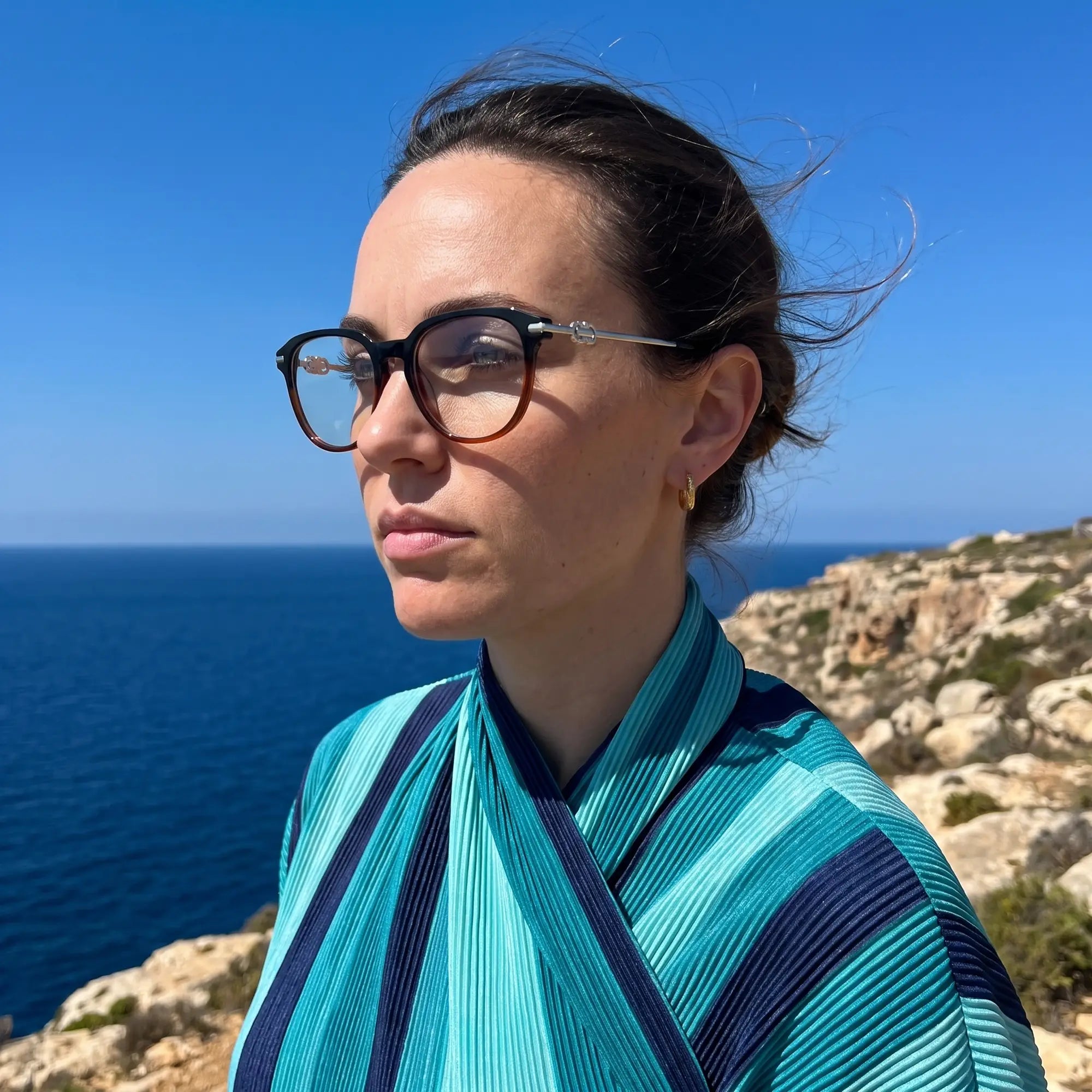 Fiore 5409 eyeglasses in black brown, worn by a model – campaign portrait, windswept portrait over the deep blue sea