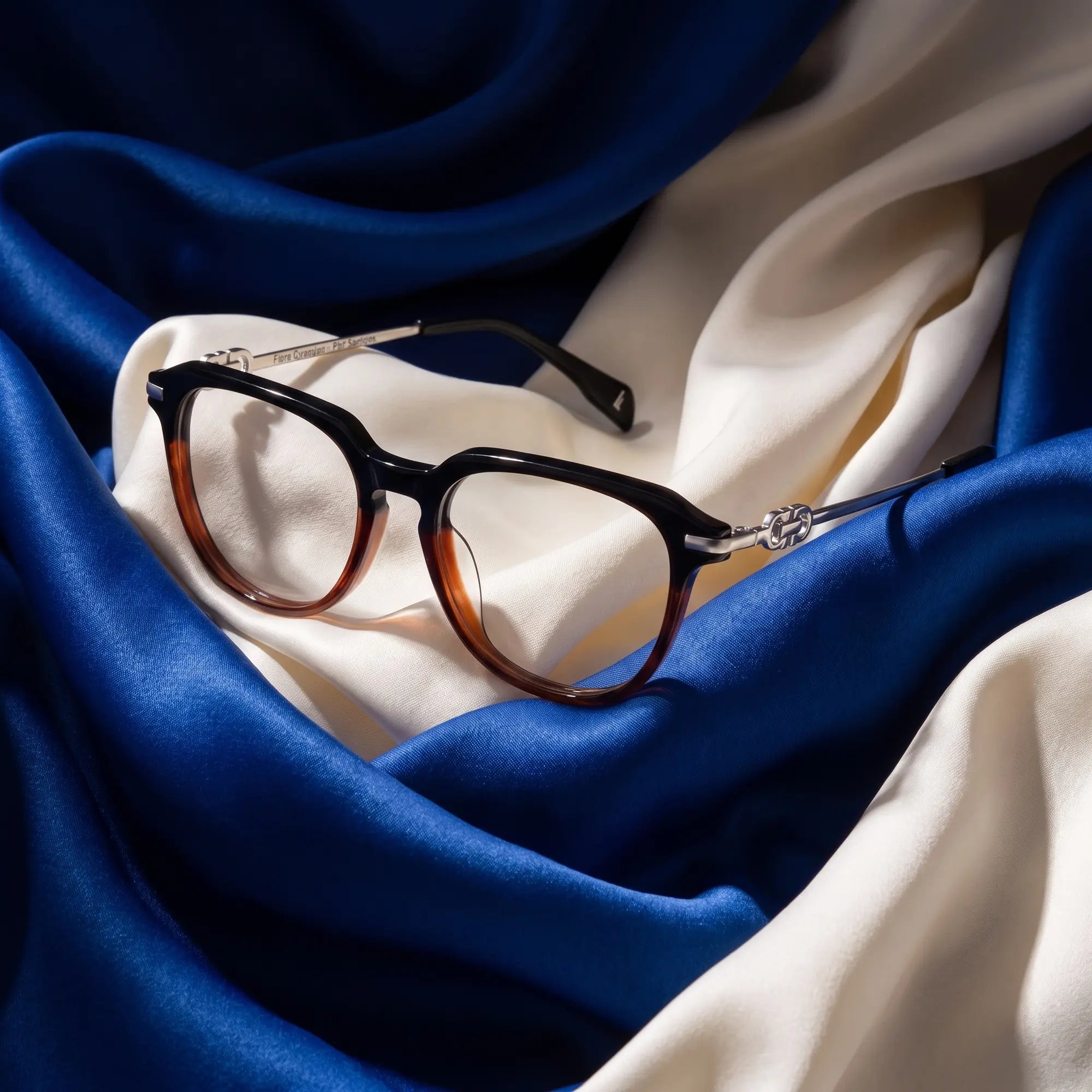 Fiore 5409 eyeglasses in black brown – resting on draped cobalt and ivory silk