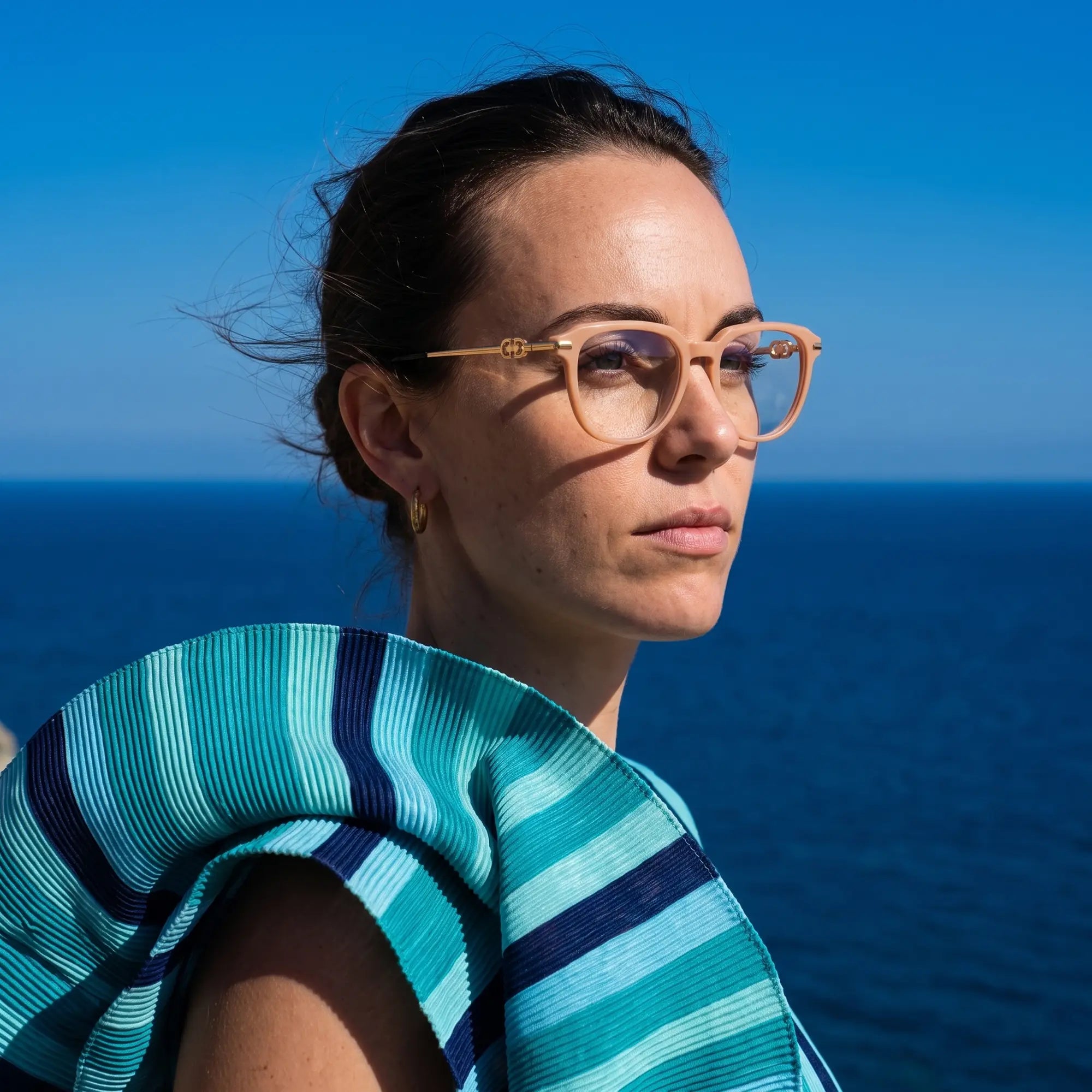 Fiore 5409 eyeglasses in milky white, worn by a model – campaign portrait, windswept portrait over the deep blue sea
