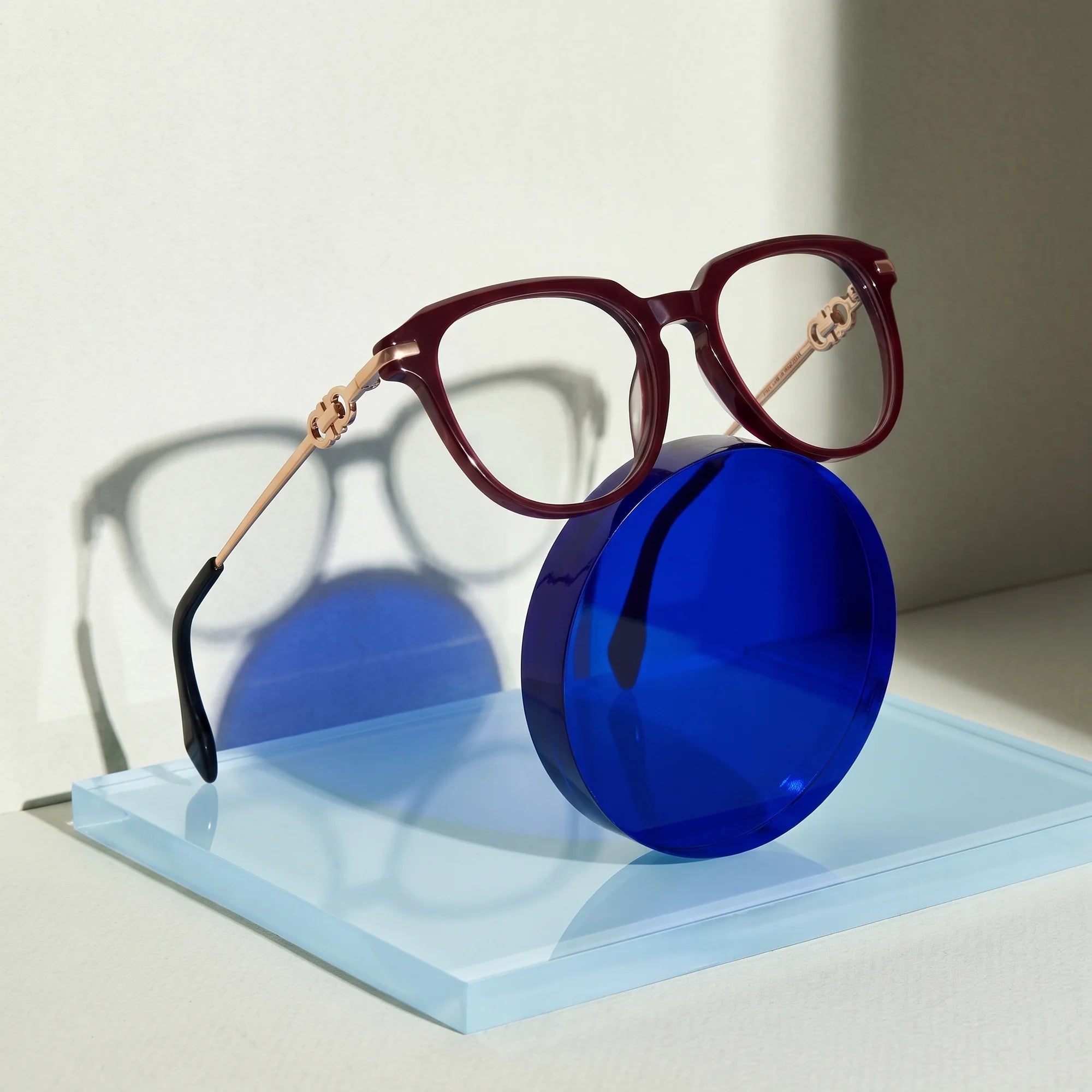 Fiore 5409 eyeglasses in brown red – on a cobalt acrylic disc in soft daylight