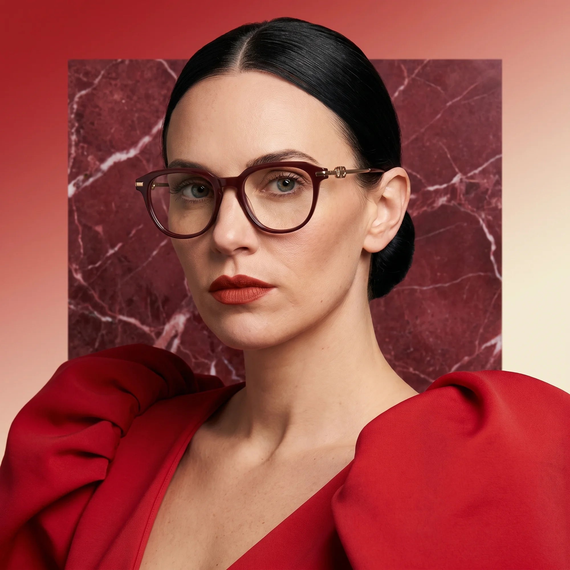 Fiore 5409 eyeglasses in brown red, worn by a model – campaign portrait, red marble backdrop and draped scarlet dress