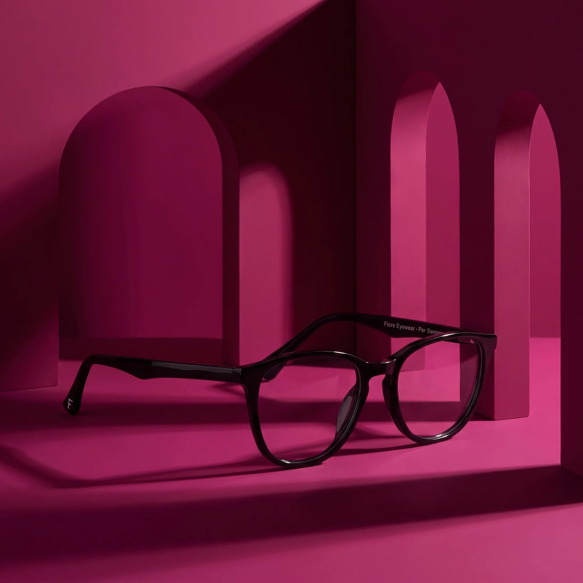 Fiore 7046 eyeglasses in black – staged on a sculptural magenta architecture set