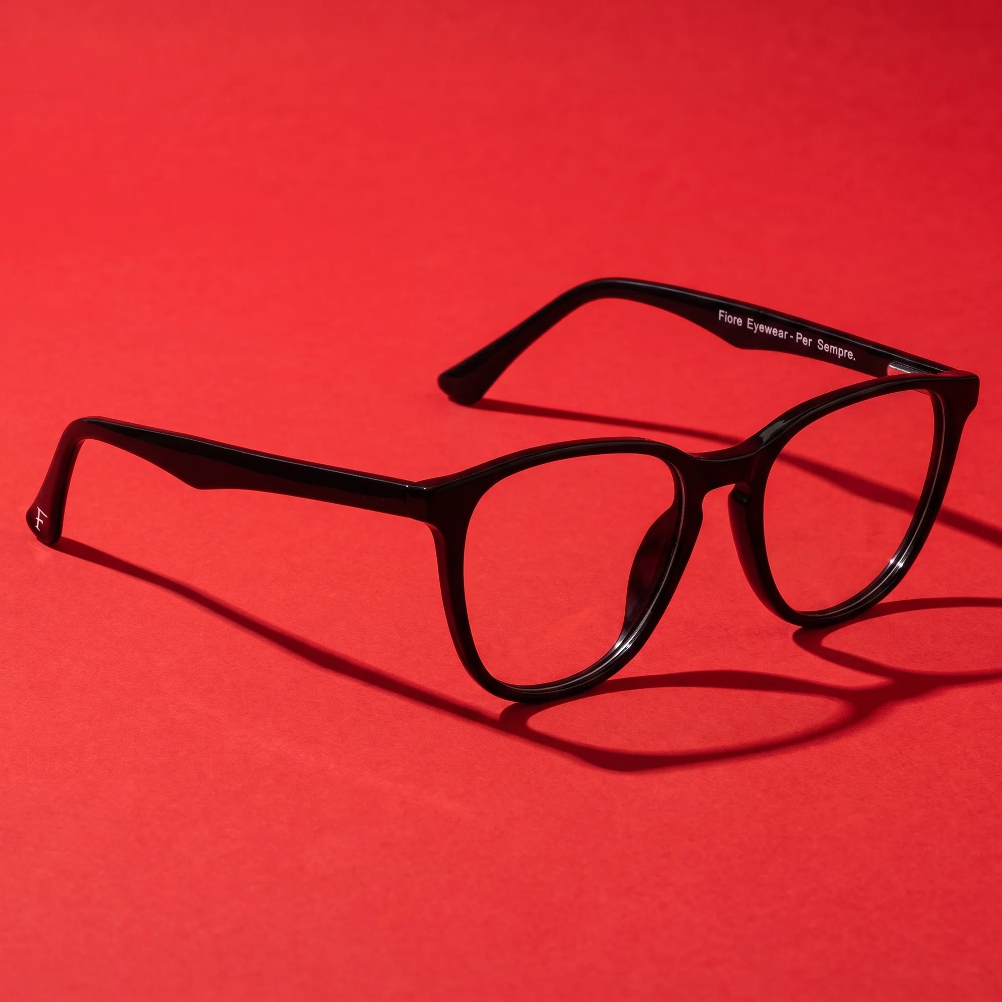 Fiore 7046 eyeglasses in black – editorial still life on a saturated vivid red set