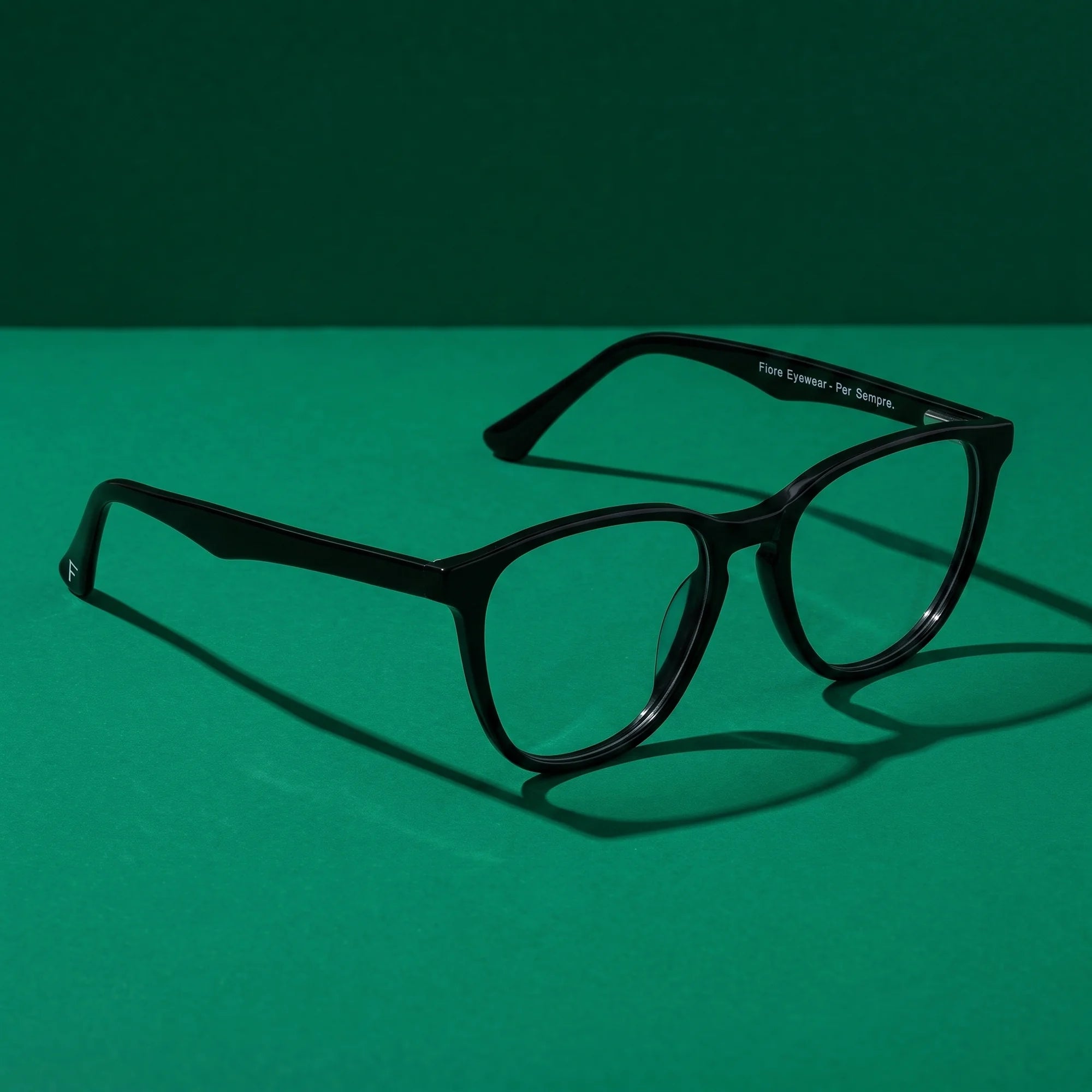Fiore 7046 eyeglasses in black – still life on a seamless emerald studio backdrop