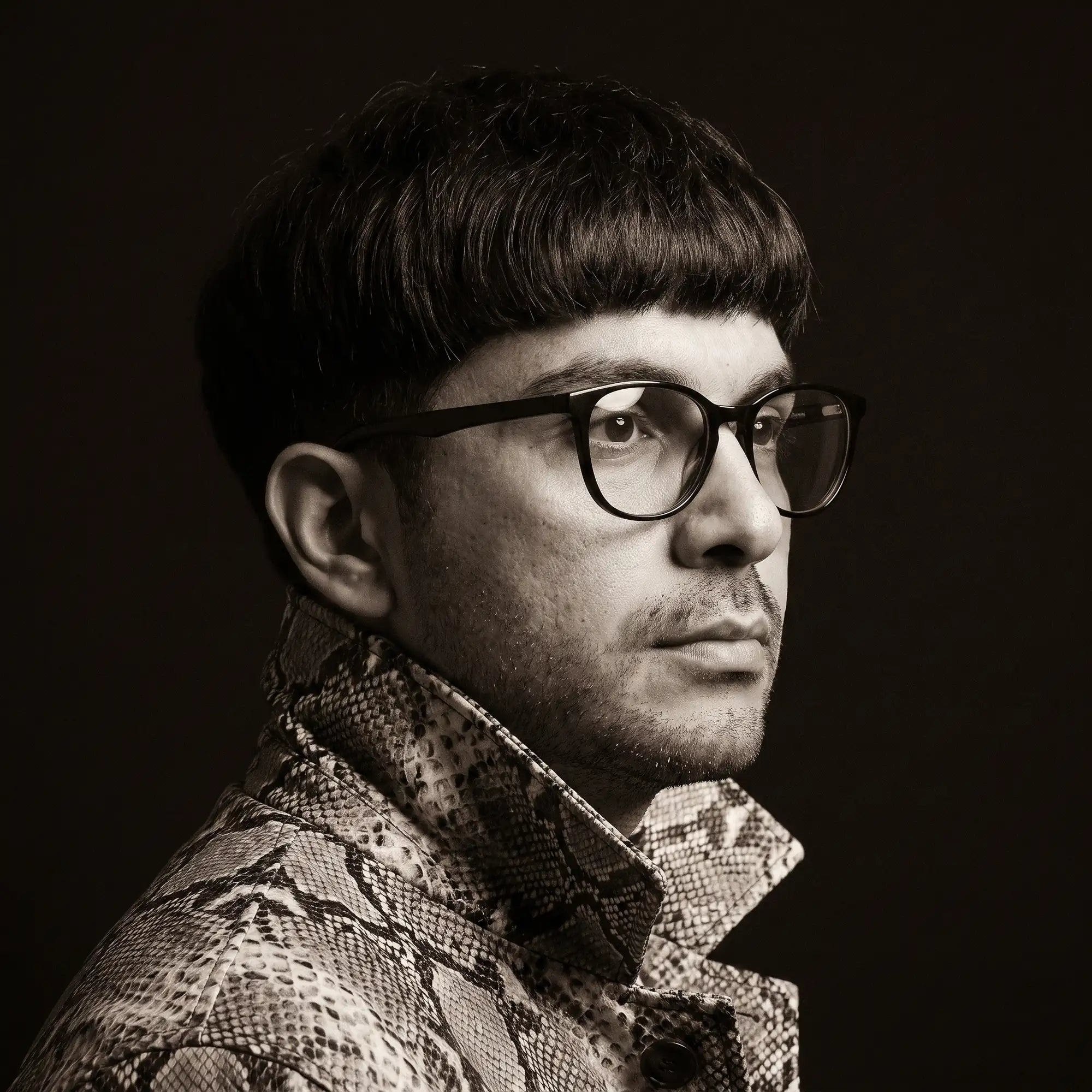Fiore 7046 eyeglasses in black, worn by a model – campaign portrait, monochrome studio portrait, red graphic accents