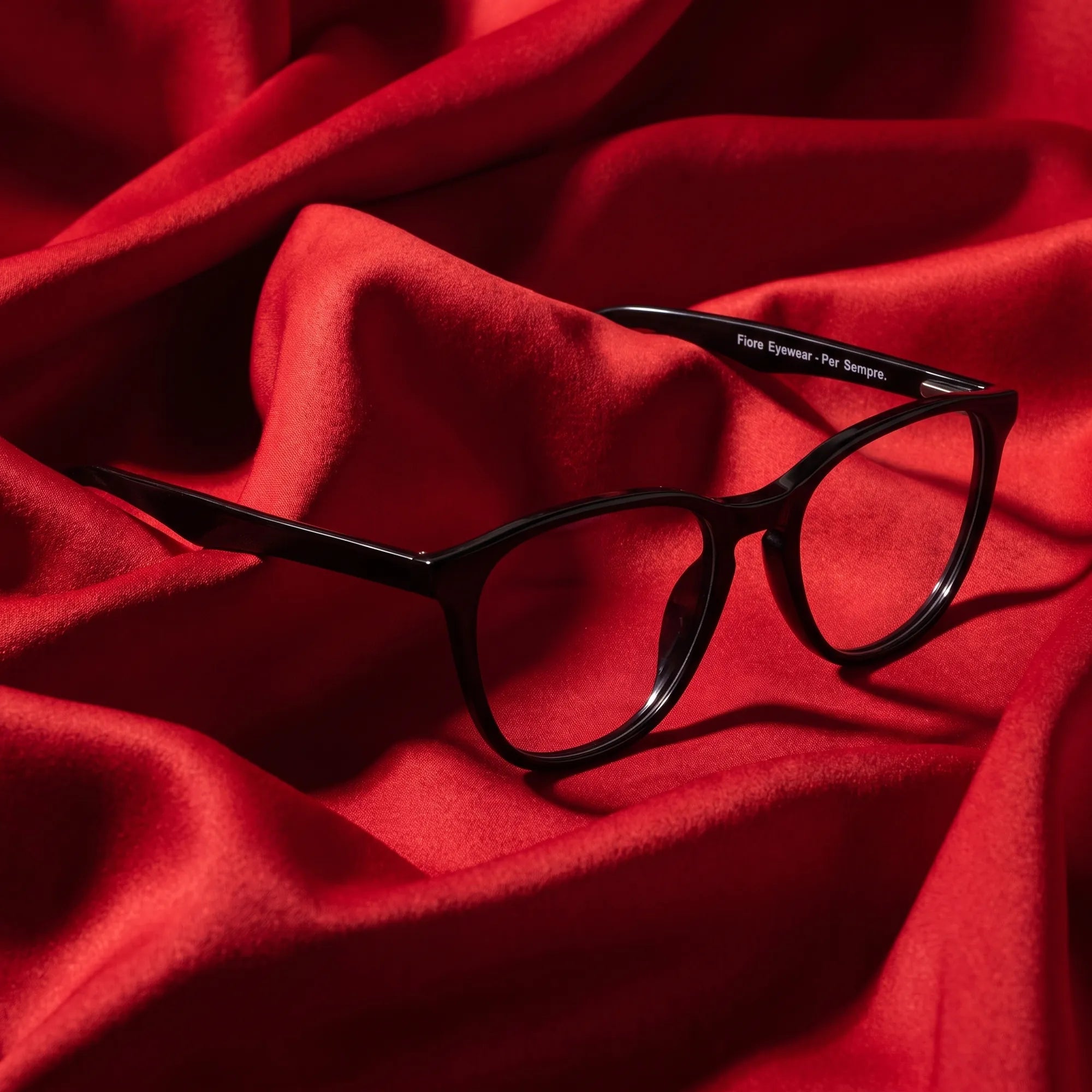 Fiore 7046 eyeglasses in black – nested in flowing vivid red silk